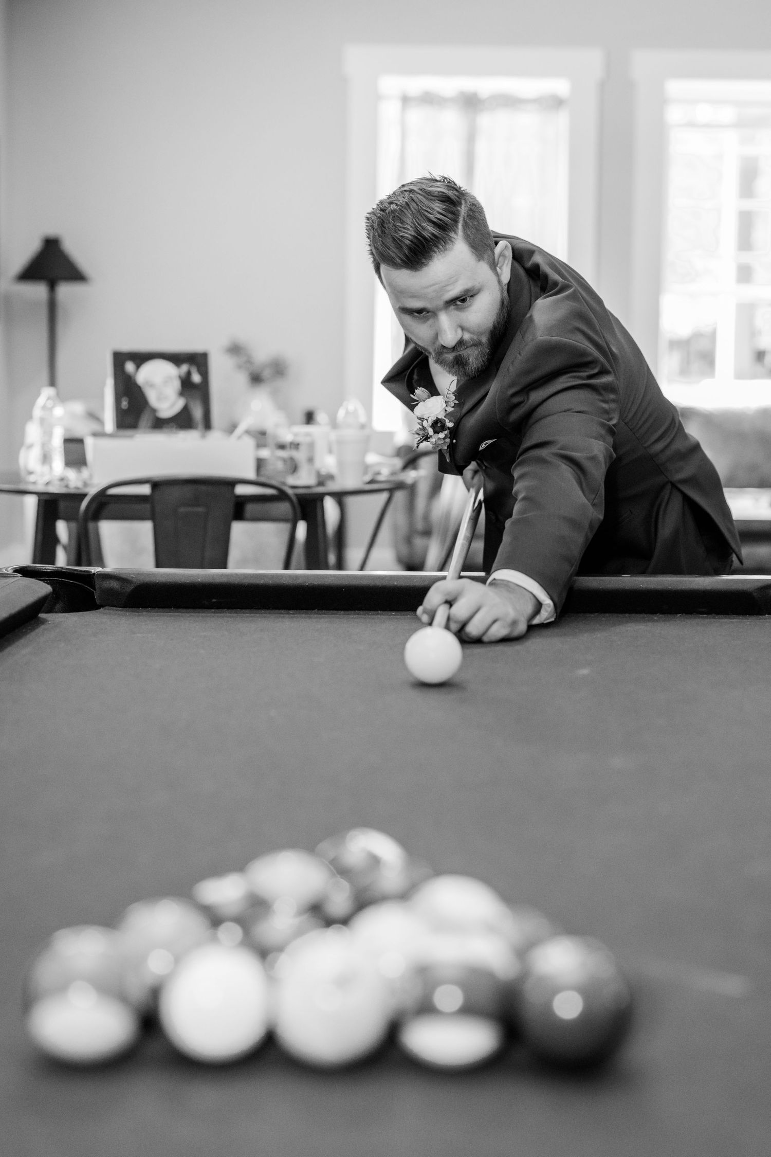 Black and white photo series of someone playing pool on a billiards table in formal attire.