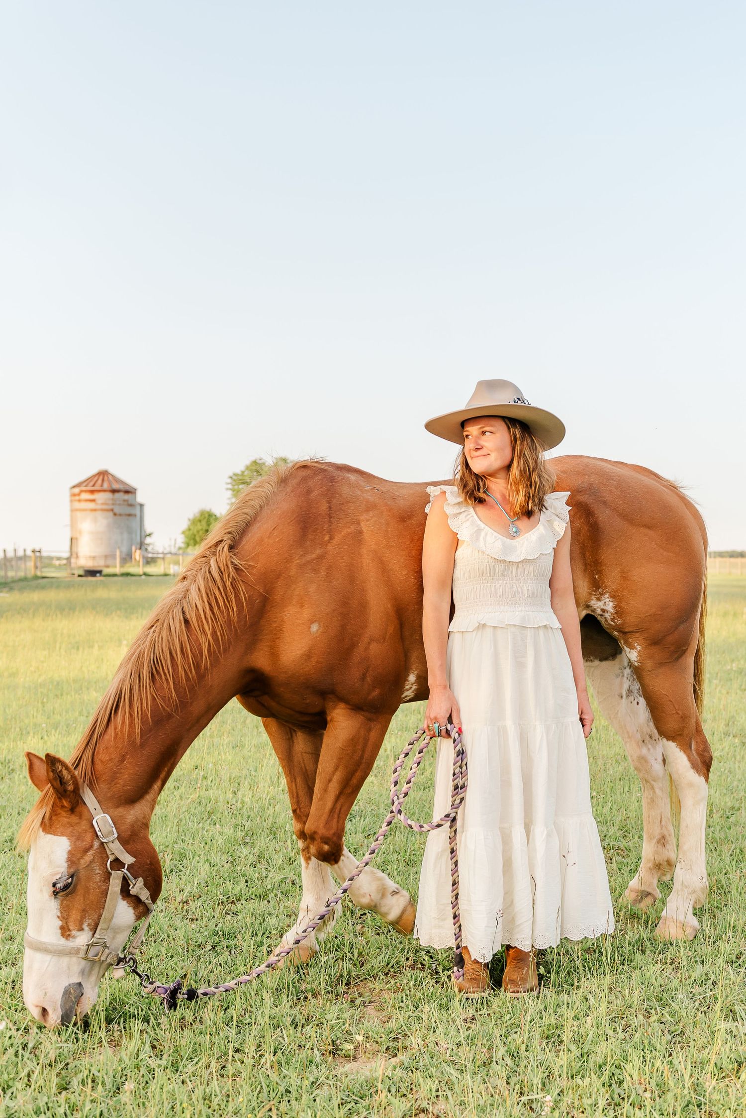 A series of three photos showing someone in a white dress standing beside grazing brown horses in a green pasture.