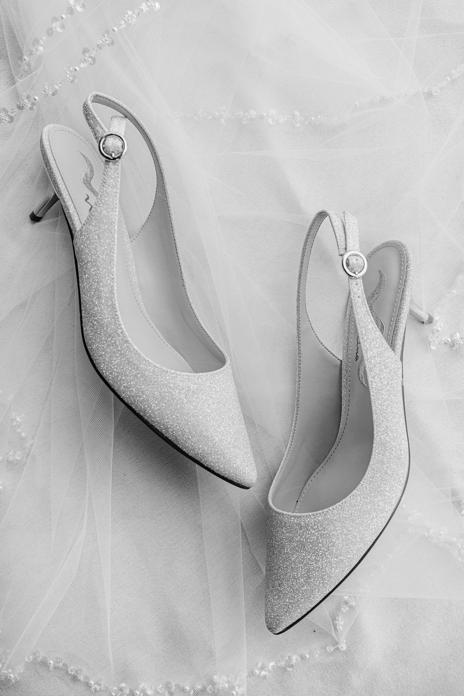 Elegant silver glitter wedding heels arranged in a row on white marble background. The Old Barns at Dry Run Farms in Williamsport, OH.