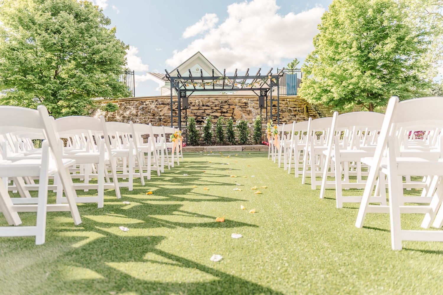 White folding chairs arranged in rows on a lush green lawn for an outdoor wedding ceremony.