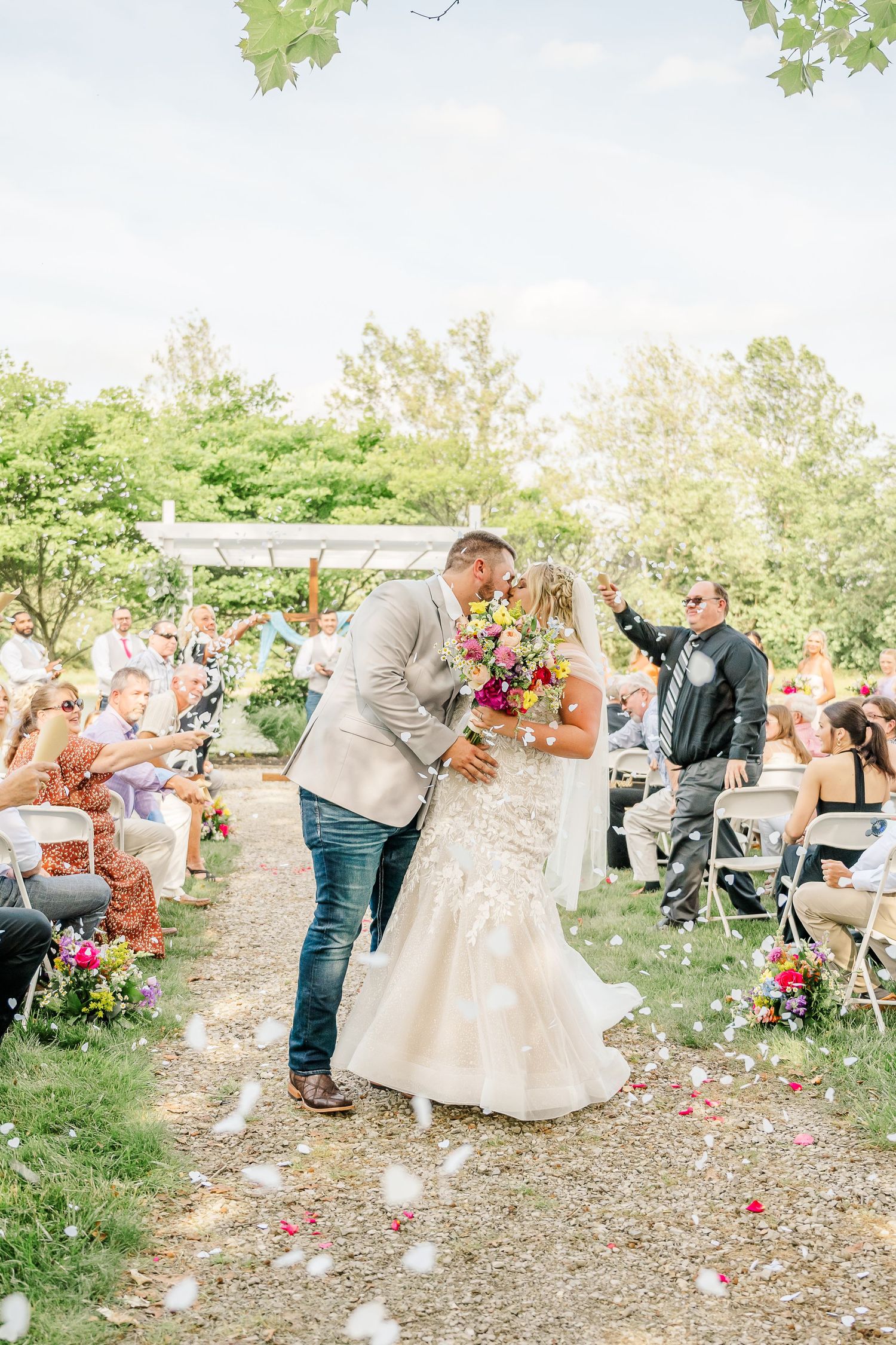 Wedding celebration sequence showing guests tossing rose petals during a joyful recessional on a garden path.