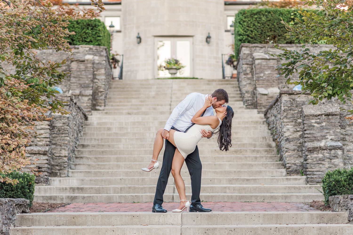 Couple poses playfully on grand stone steps during romantic photoshoot.