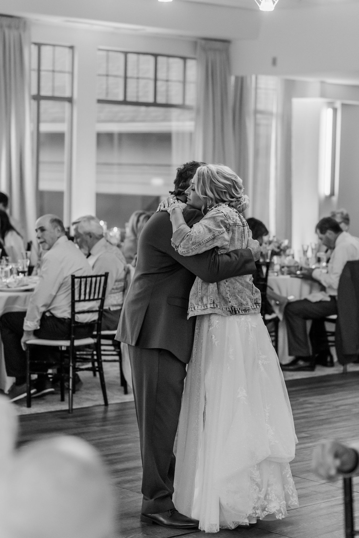 A tender black and white moment captured at a wedding reception as a couple shares an intimate embrace on the dance floor.
