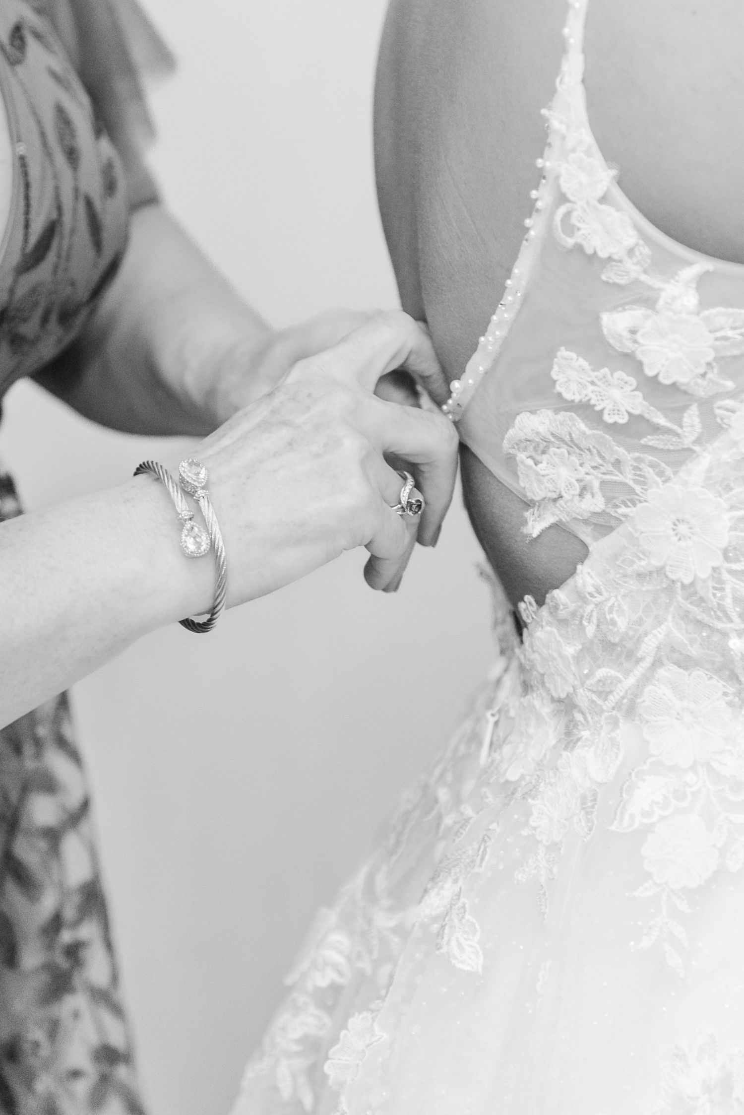 Close-up view of someone adjusting delicate white lace details on an elegant wedding dress.