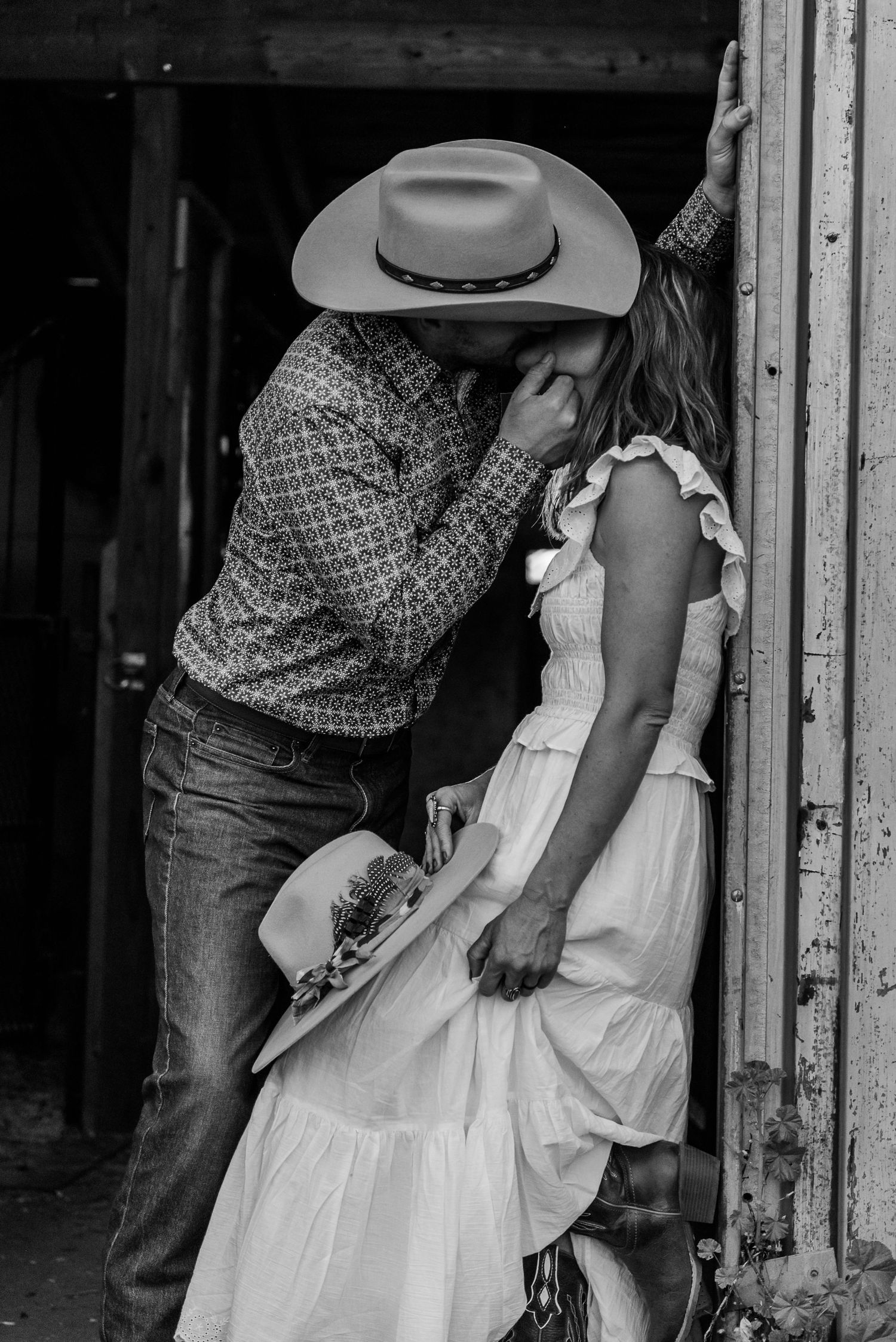 Artistic black and white photo series showing intimate moments between a couple near barn doors.