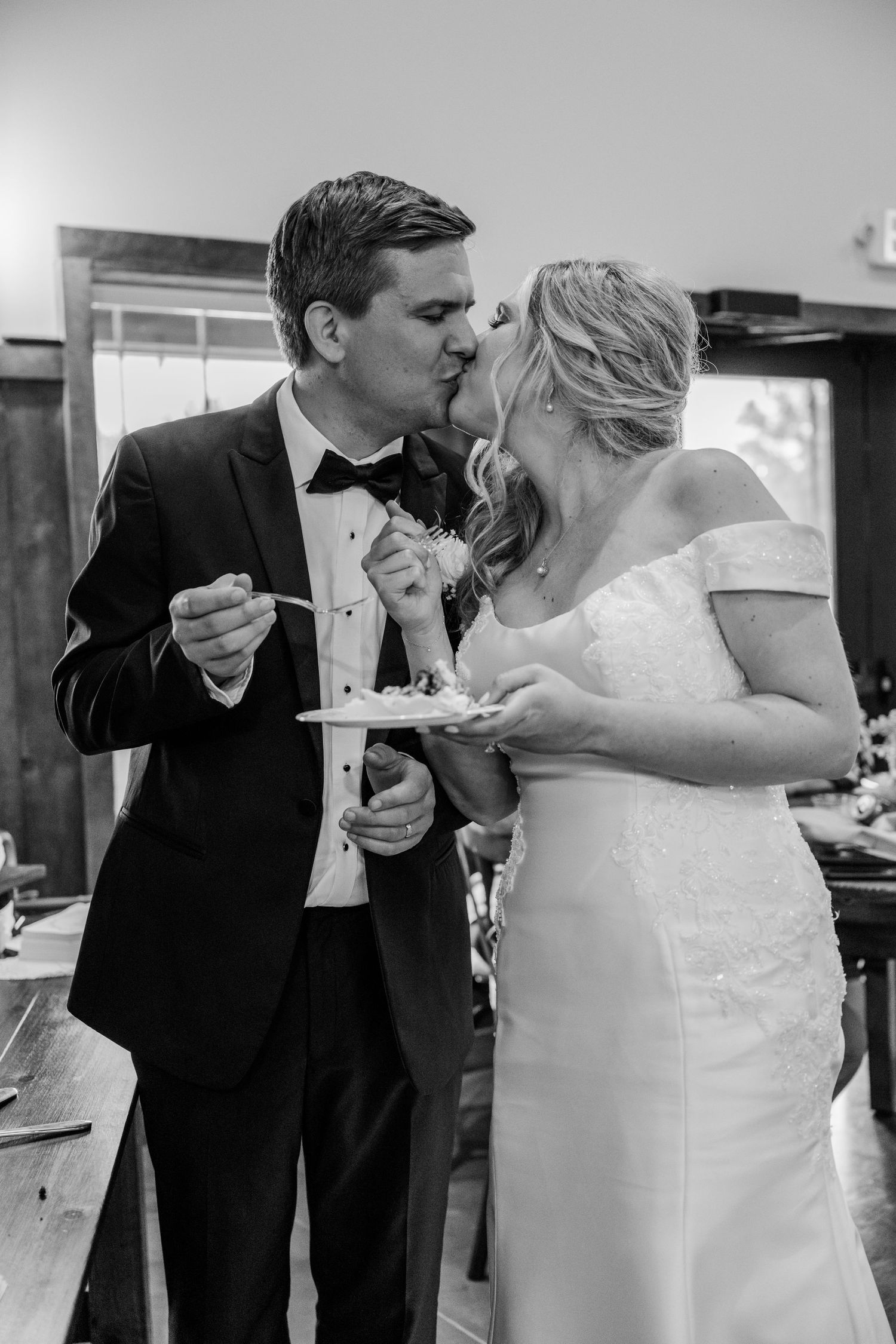A couple shares a sweet moment while eating their wedding cake together at the reception.