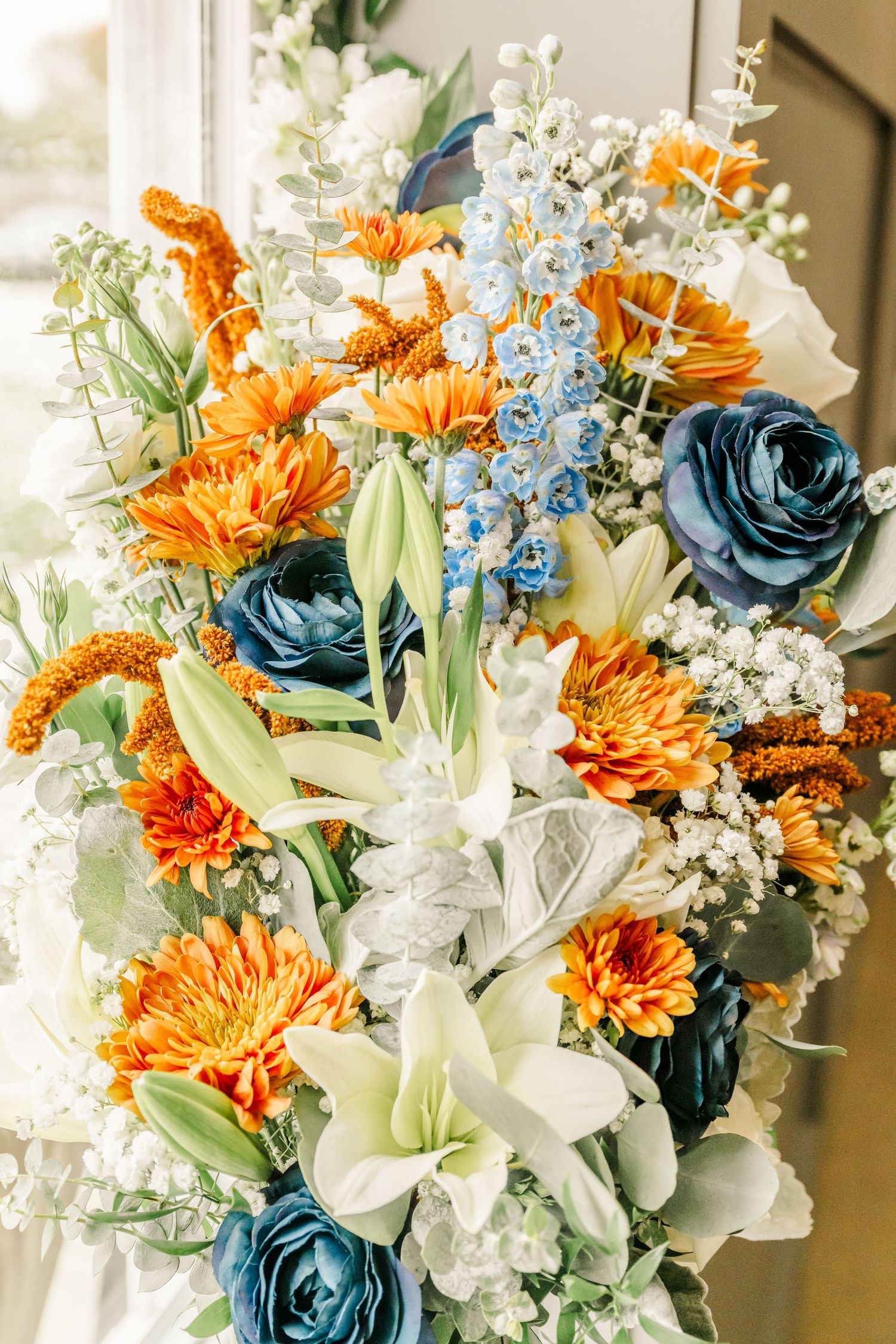 Beautiful wedding bouquet featuring white lilies, orange chrysanthemums, teal roses and baby's breath flowers.