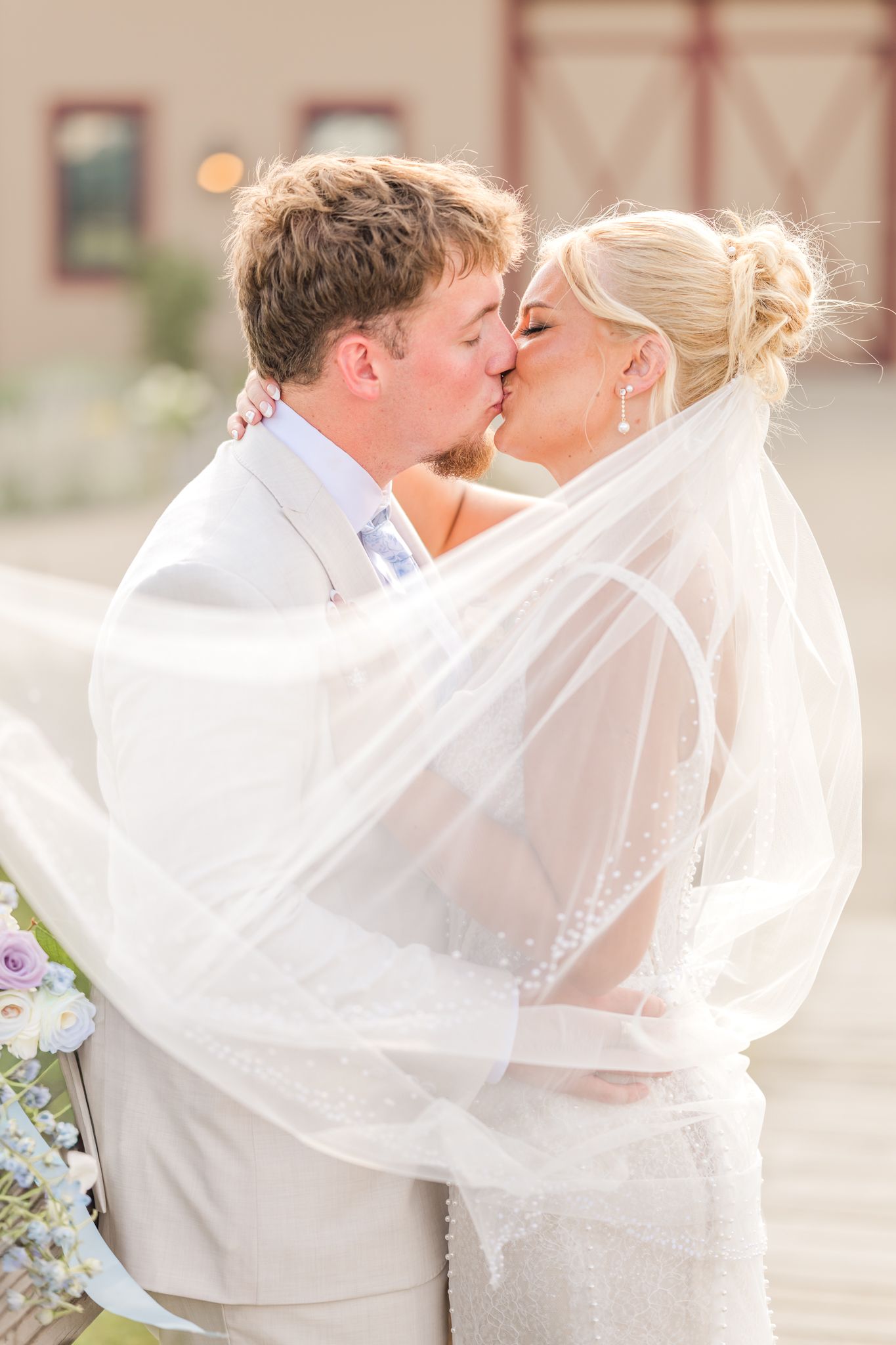 A bride and groom share a romantic kiss under a flowing white veil on their wedding day. Peacock Ridge in North Lawerence, Ohio.