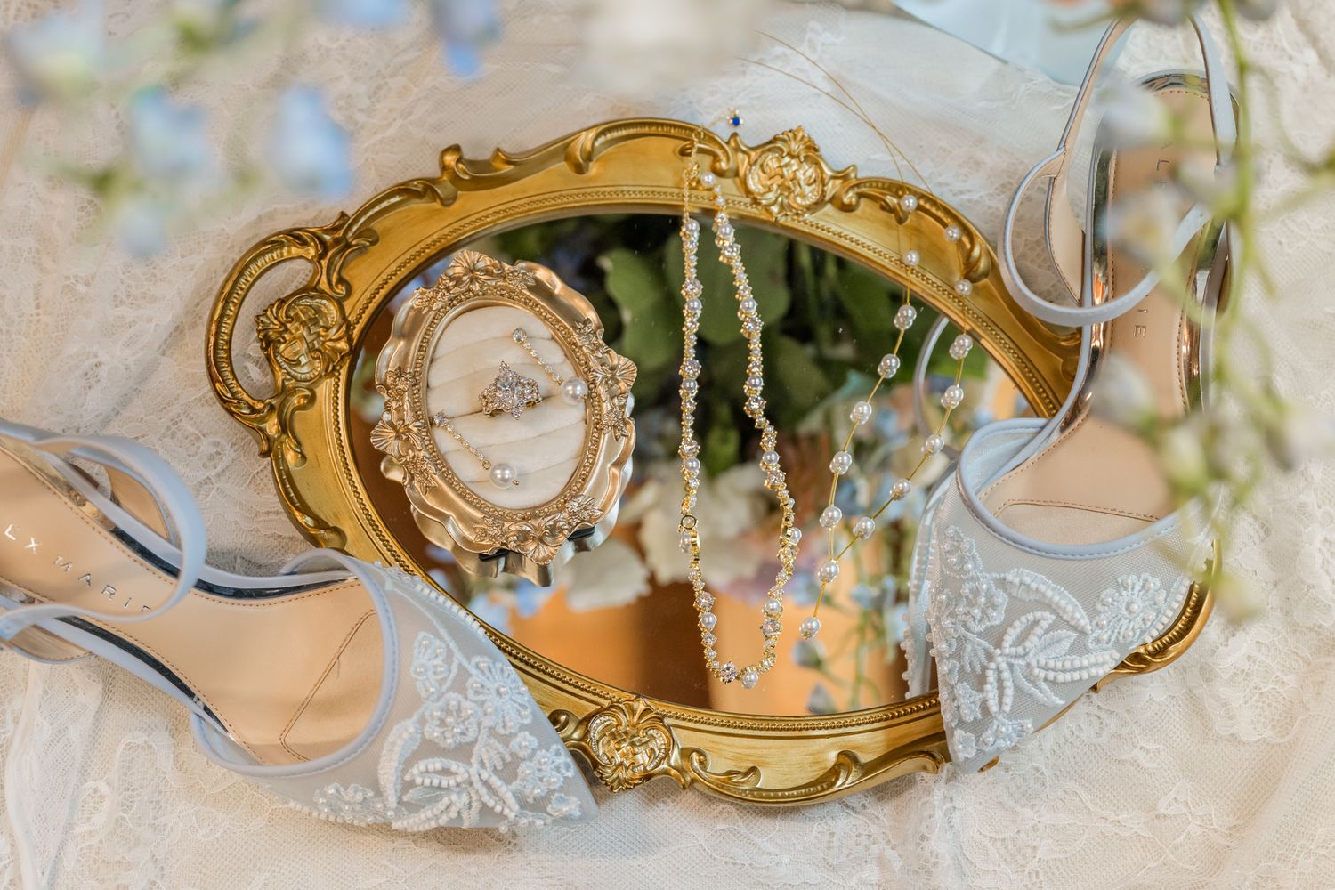 Gold ornate mirror tray with wedding ring, pearl necklace, and blue bridal heels on lace fabric. Peacock Ridge wedding venue in Ohio.