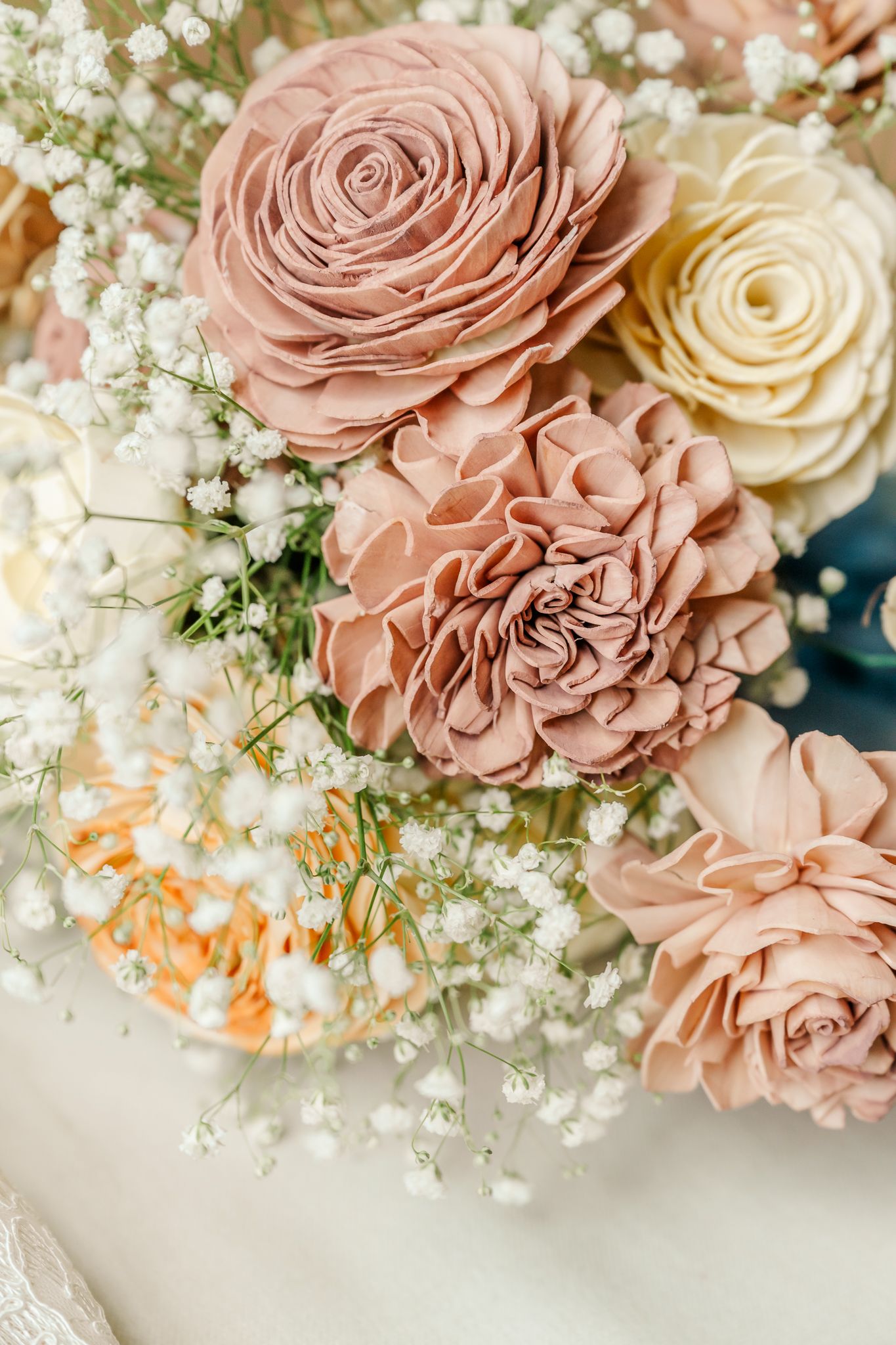 Elegant bouquet of dusty rose sola wood flowers and baby's breath in soft blush and cream tones for a wedding.