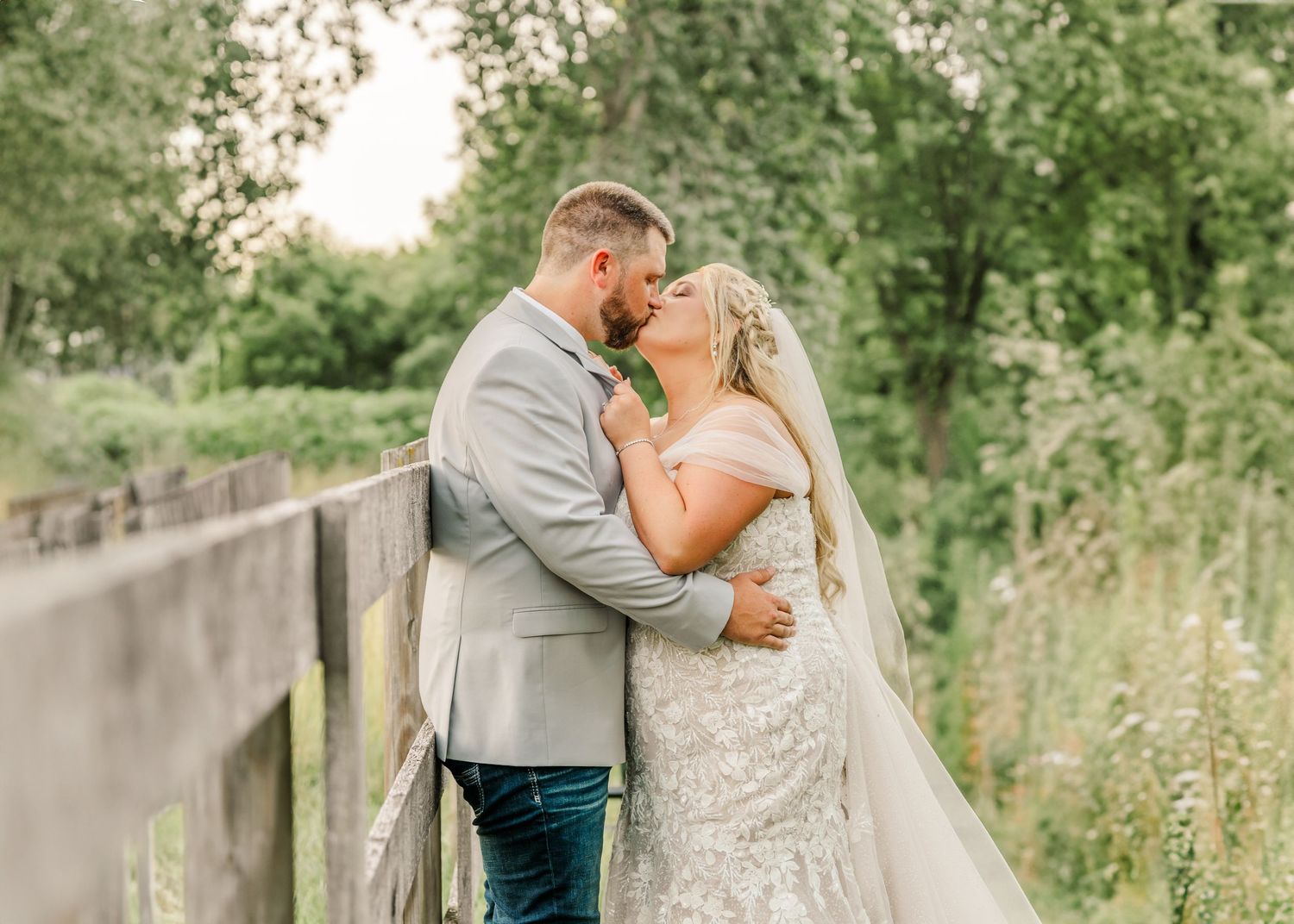 A couple shares a romantic moment in a lush garden setting wearing formal wedding attire.