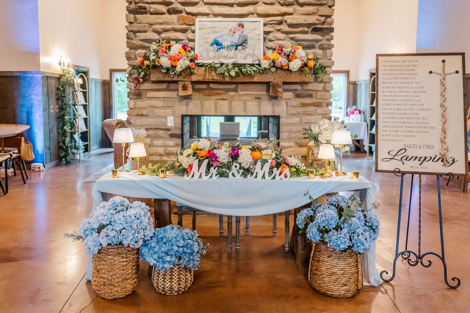 Rustic stone wall venue decorated with floral arrangements and elegant event decor in soft blue lighting.