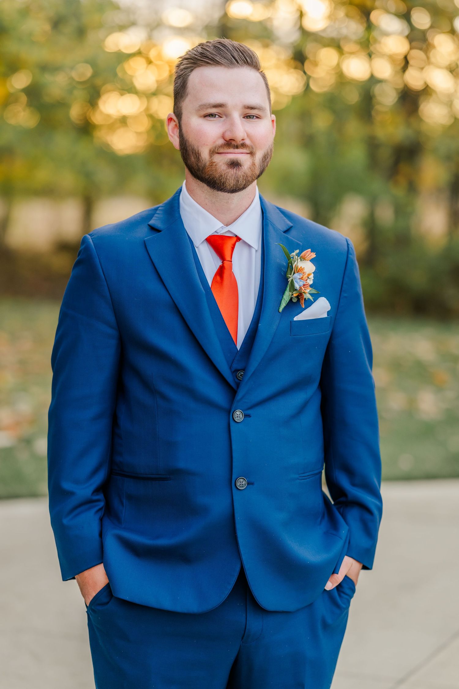 Groomsmen in navy blue suits with bright red ties pose outdoors at sunset.Four Seasons Barn Wedding & Event Venue