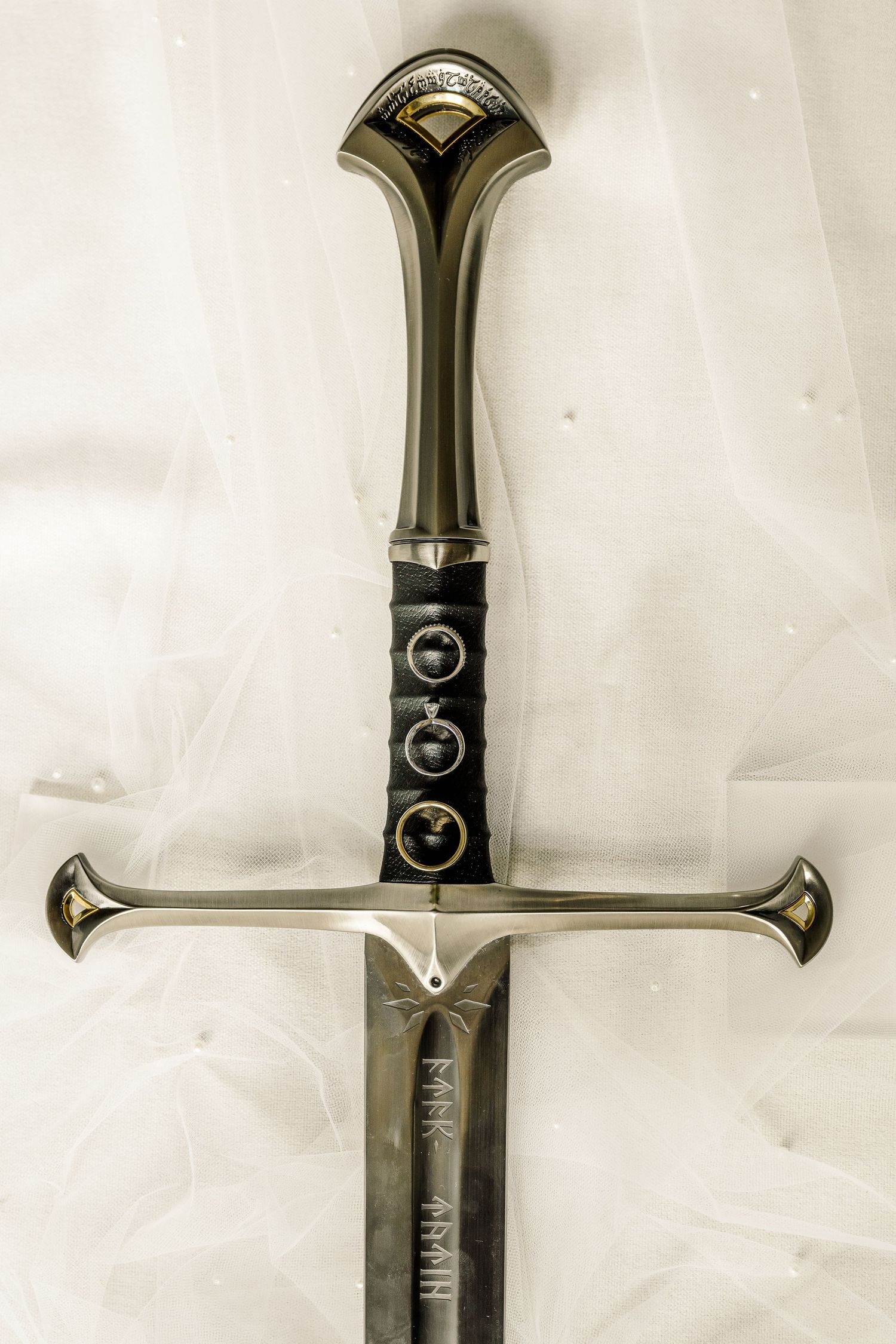 Close-up details of an ornate medieval sword hilt and pommel against a white background.