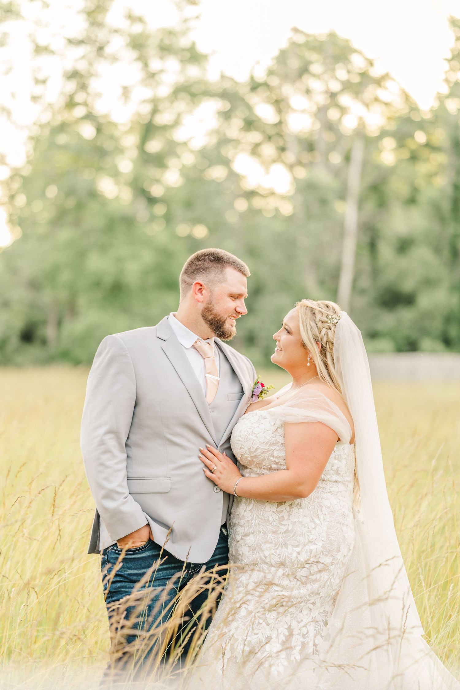 Romantic wedding portraits in sun-kissed field with golden hour lighting.