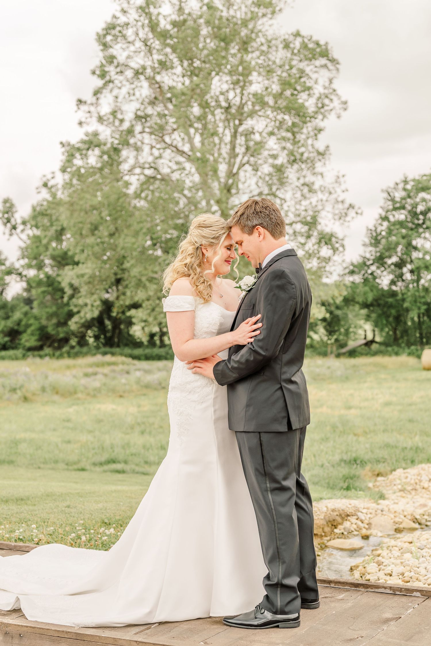 A couple shares their first look moment outdoors against a backdrop of green trees and grass.The Old Barns at Dry Run Farms in Williamsport.