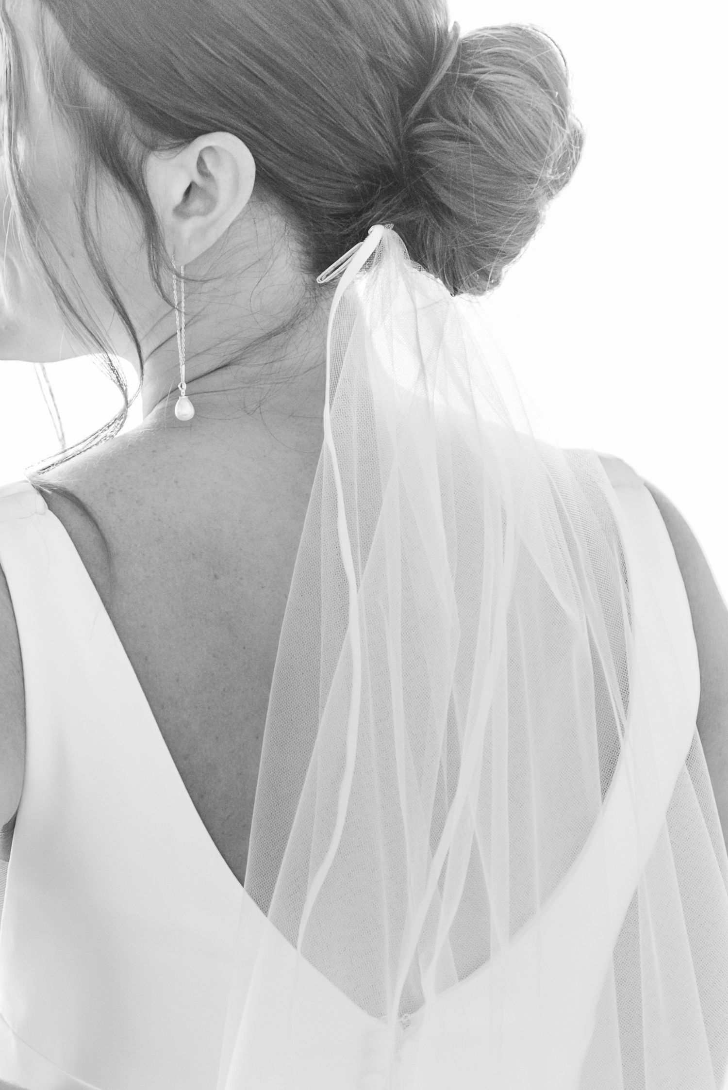 Closeup of a bride's delicate veil blowing in the wind creating an ethereal effect against a white background.