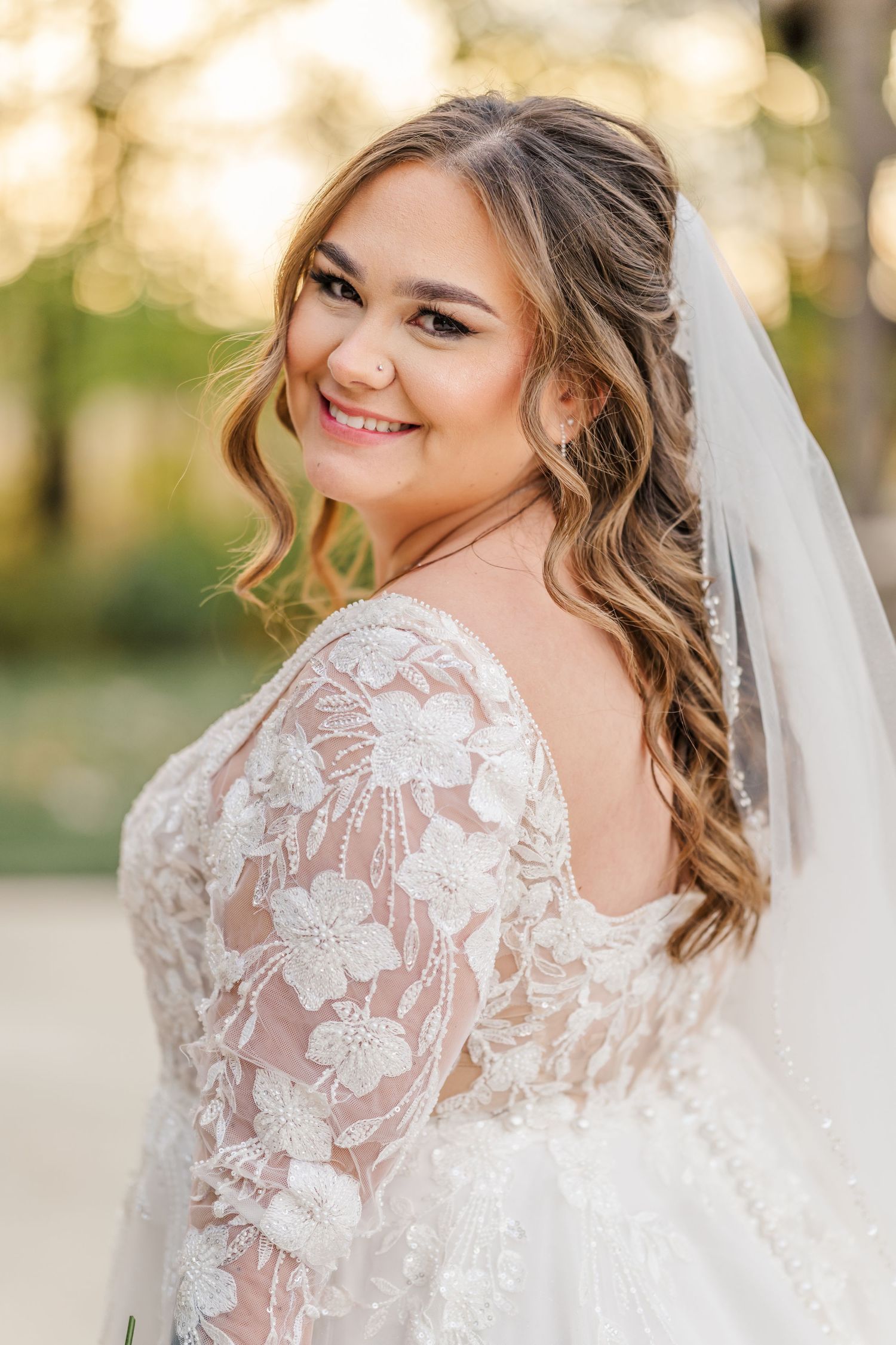 Close-up portrait of bride wearing delicate lace wedding gown and veil in natural outdoor setting.Four Seasons Barn Wedding & Event Venue