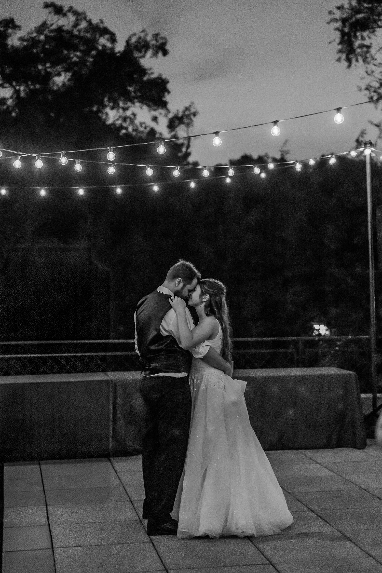 Evening wedding reception on terrace with string lights creating romantic ambiance.