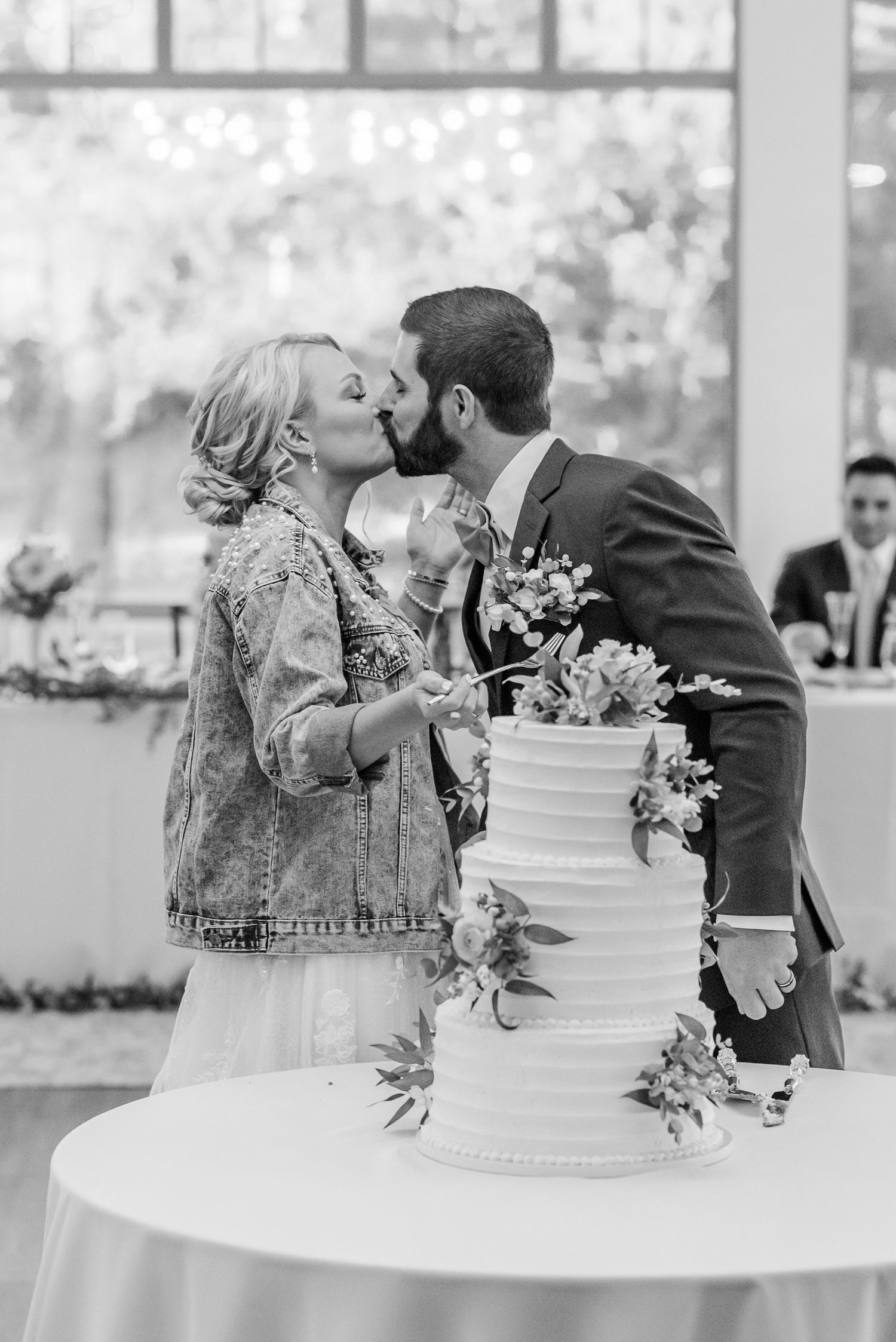 A black and white photo series of a couple cutting their elegant wedding cake at a reception.