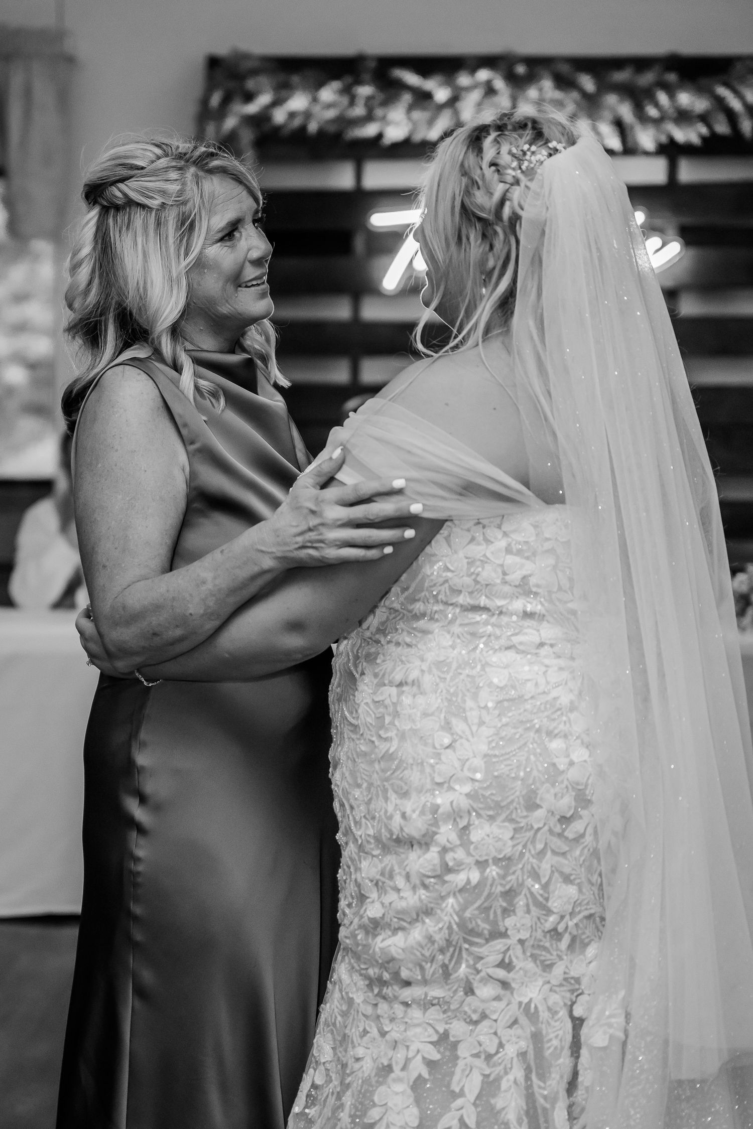 Emotional moment between mother and bride in formal attire sharing an intimate embrace before the wedding ceremony.