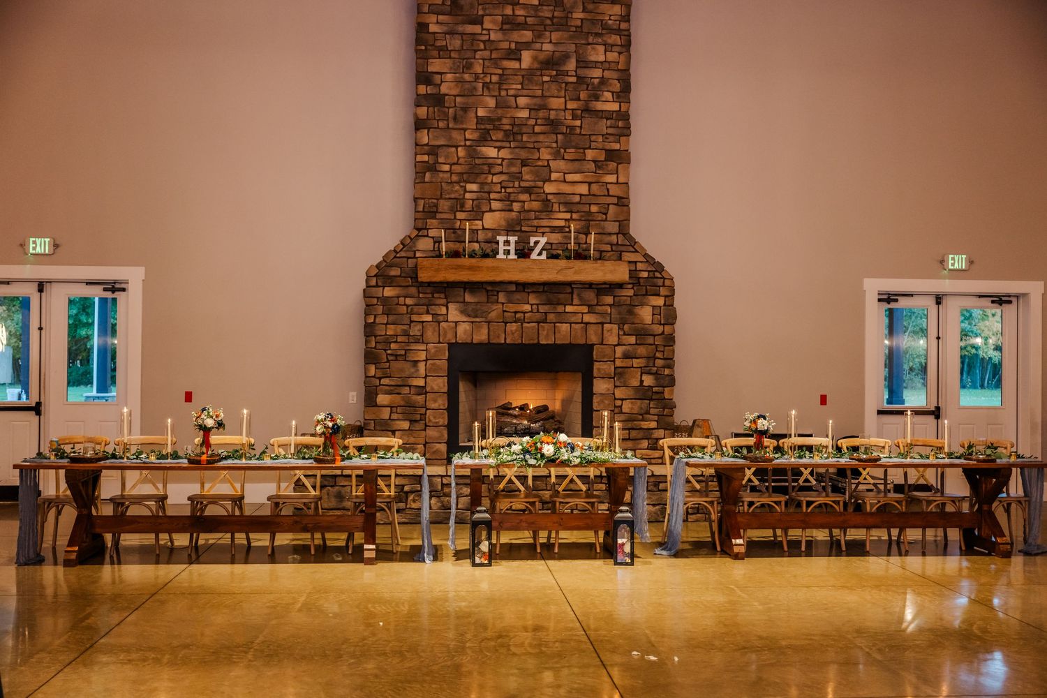 A rustic brick wall backdrop with wooden chairs and tables arranged in a banquet hall setting.Four Seasons Barn Wedding & Event Venue