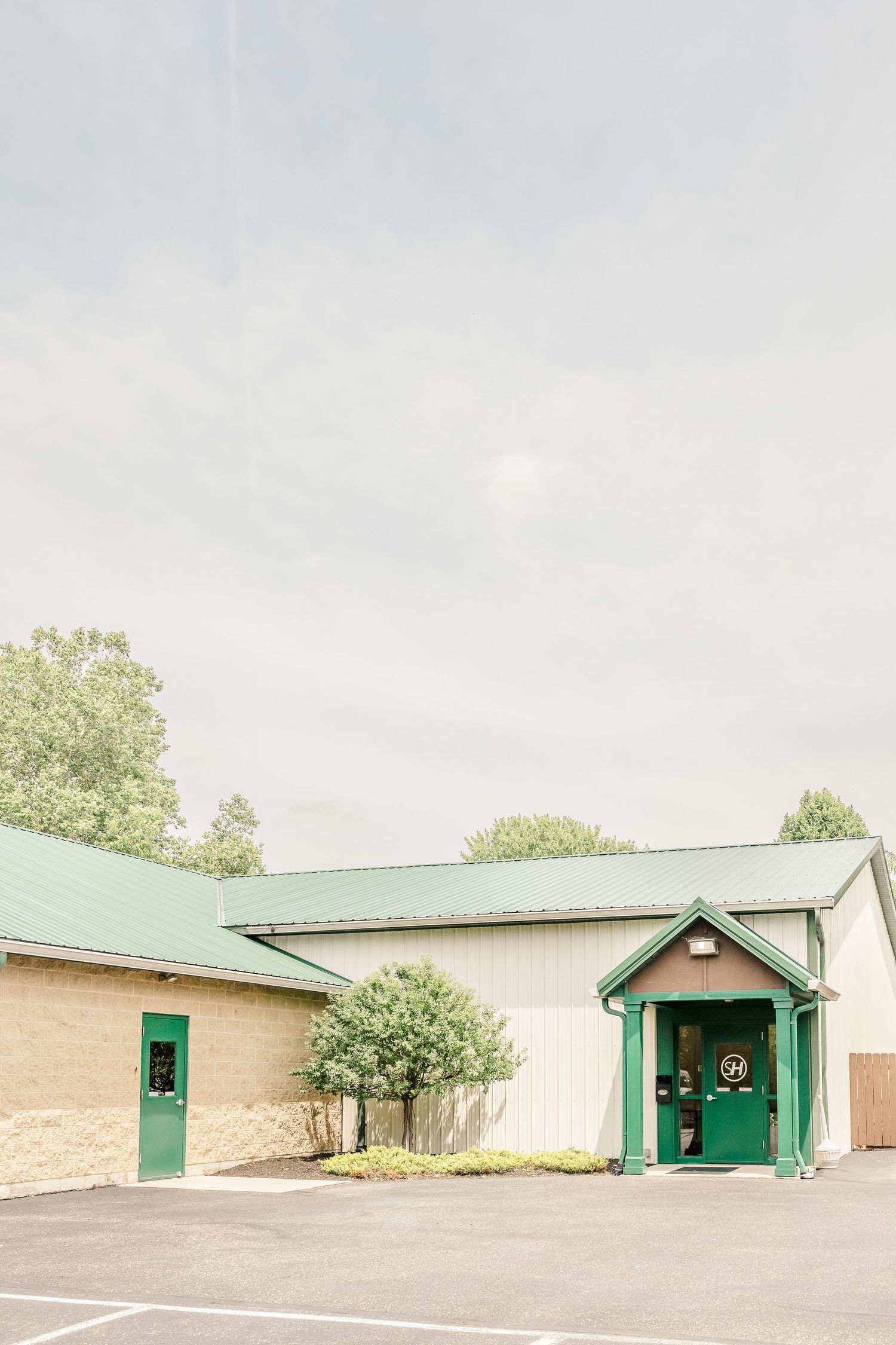 A row of beige and cream colored buildings with green trim and doors in a minimalist architectural style.
