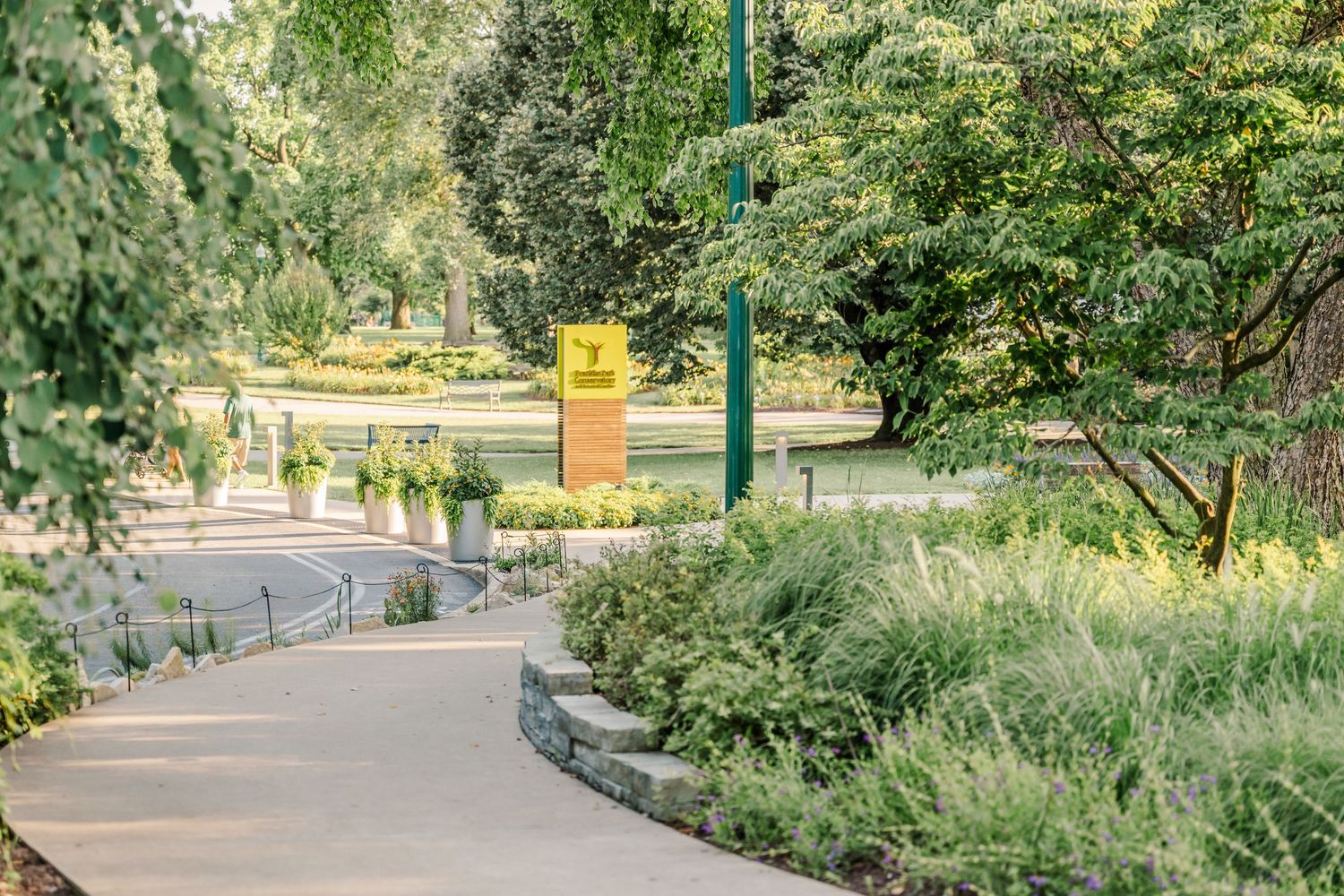 Garden pathway lined with lush greenery and trees in a formal landscaped setting.