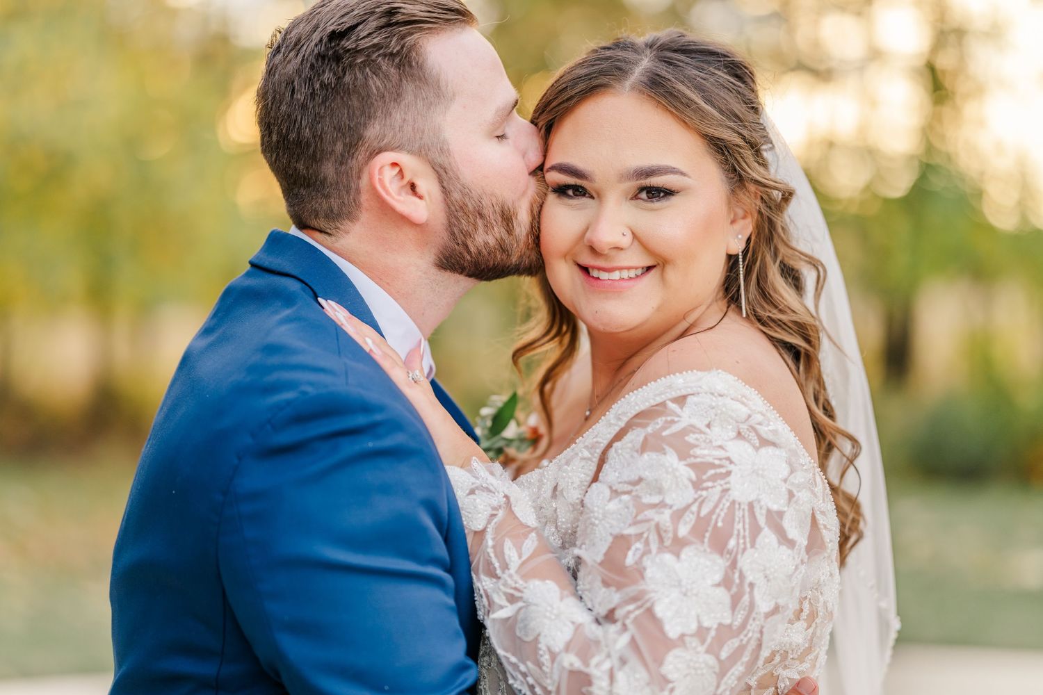 A romantic wedding photo shows a couple in formal attire embracing outdoors during golden hour.Four Seasons Barn Wedding & Event Venue