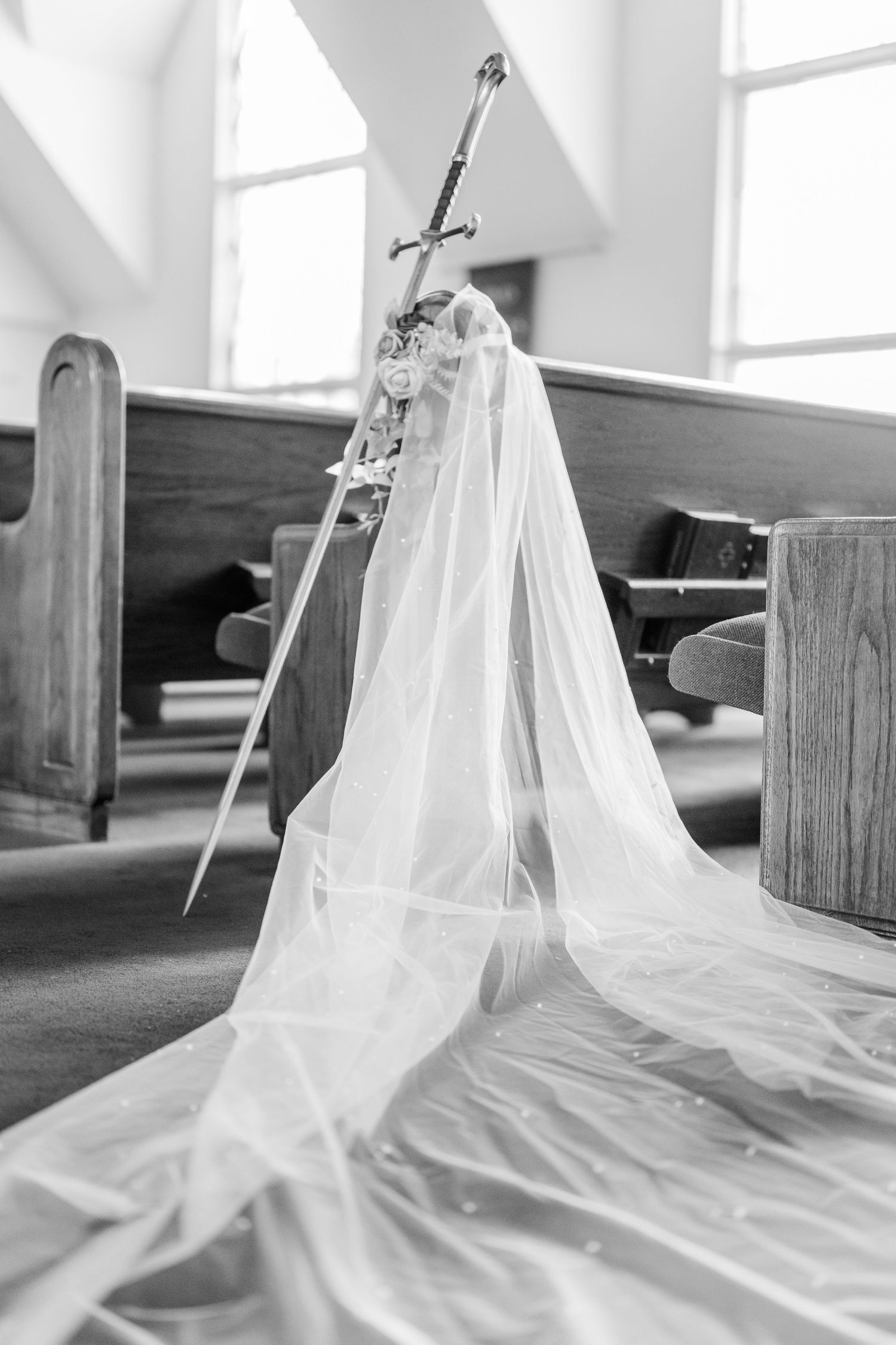 White wedding veils draped over wooden church pews in a sunlit sanctuary.