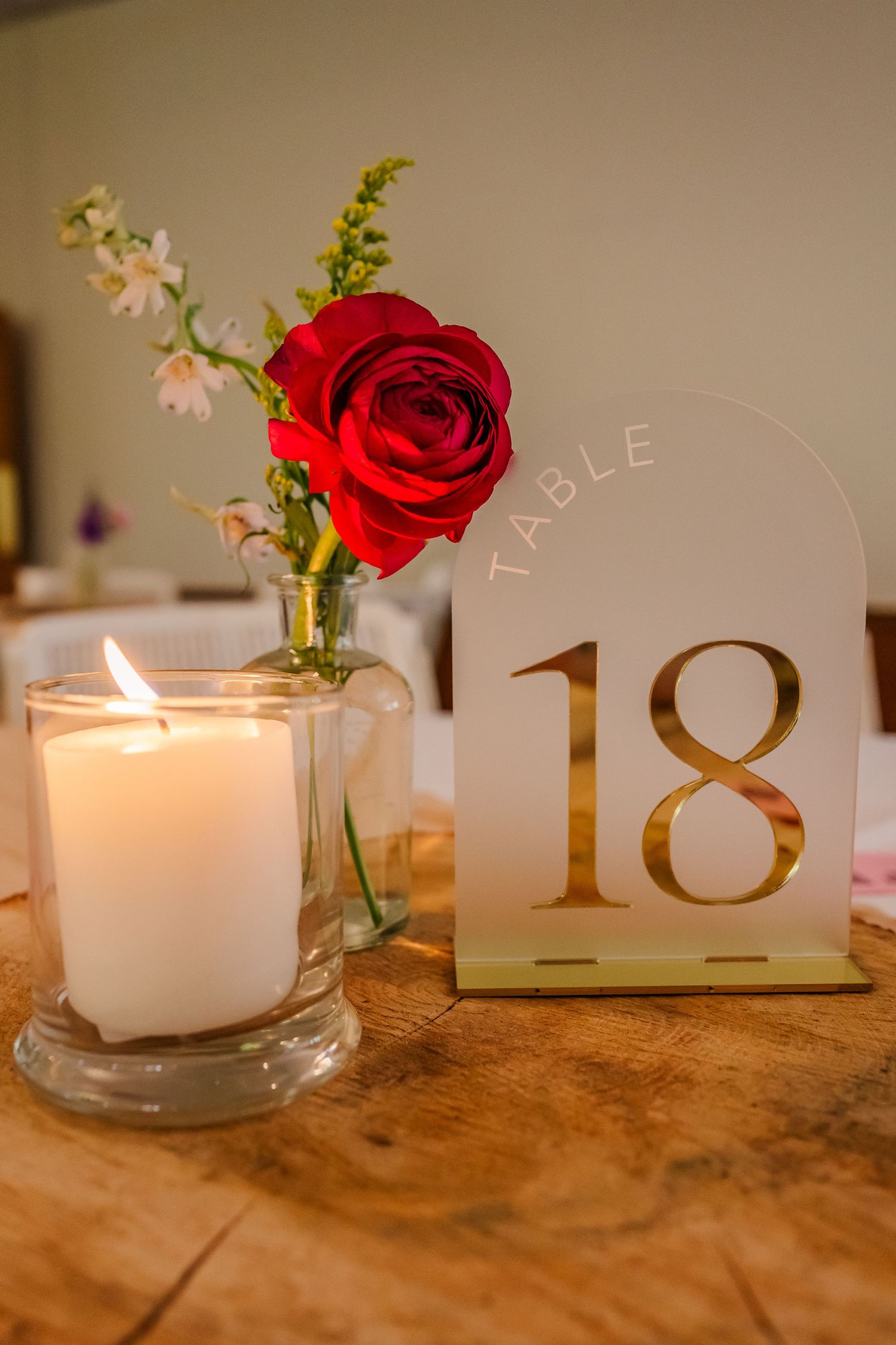 Decorative table setting with lit candles, red roses, and table numbers arranged in a romantic sequence.