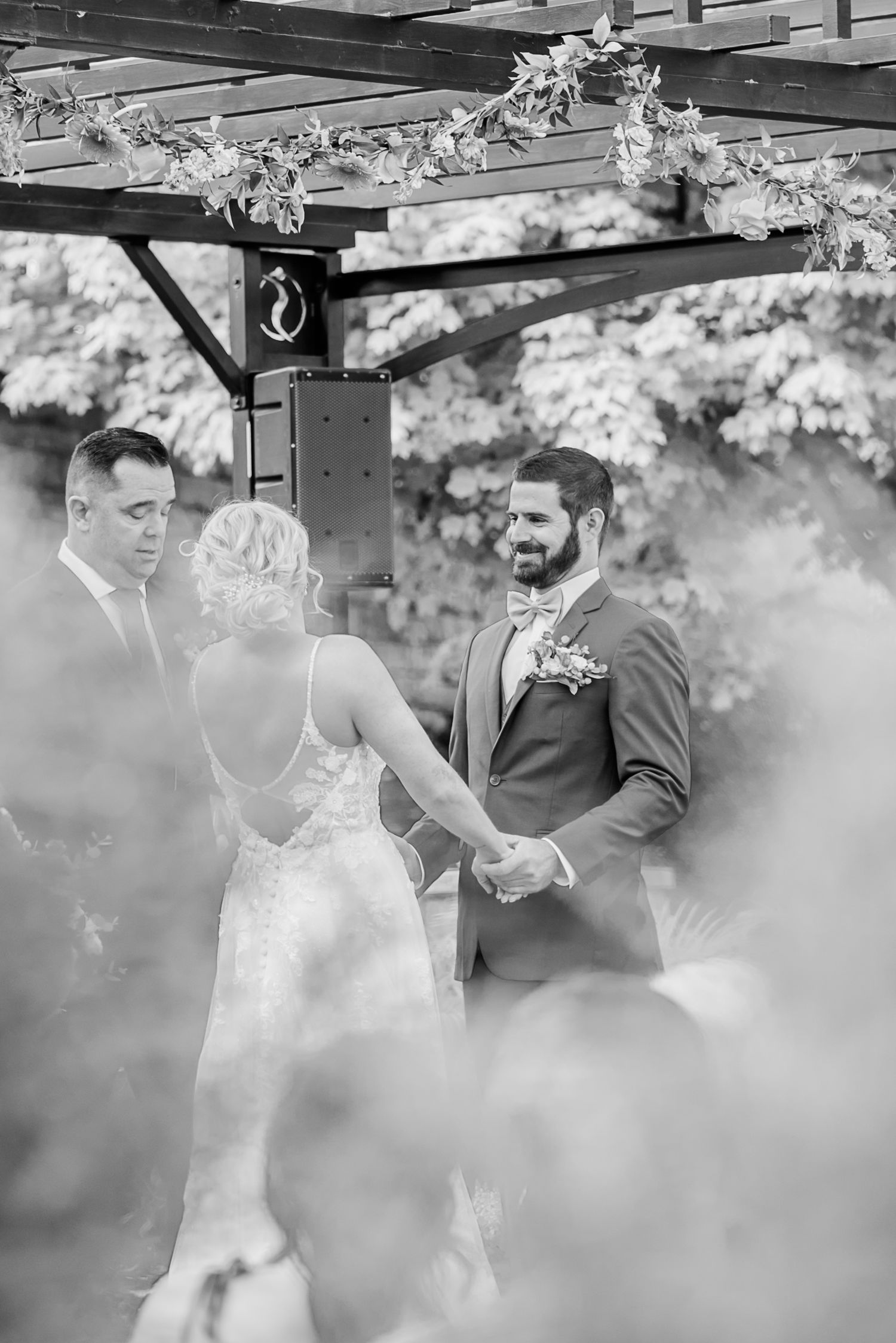 A wedding ceremony sequence captured in black and white showing tender moments under a decorated outdoor pergola.