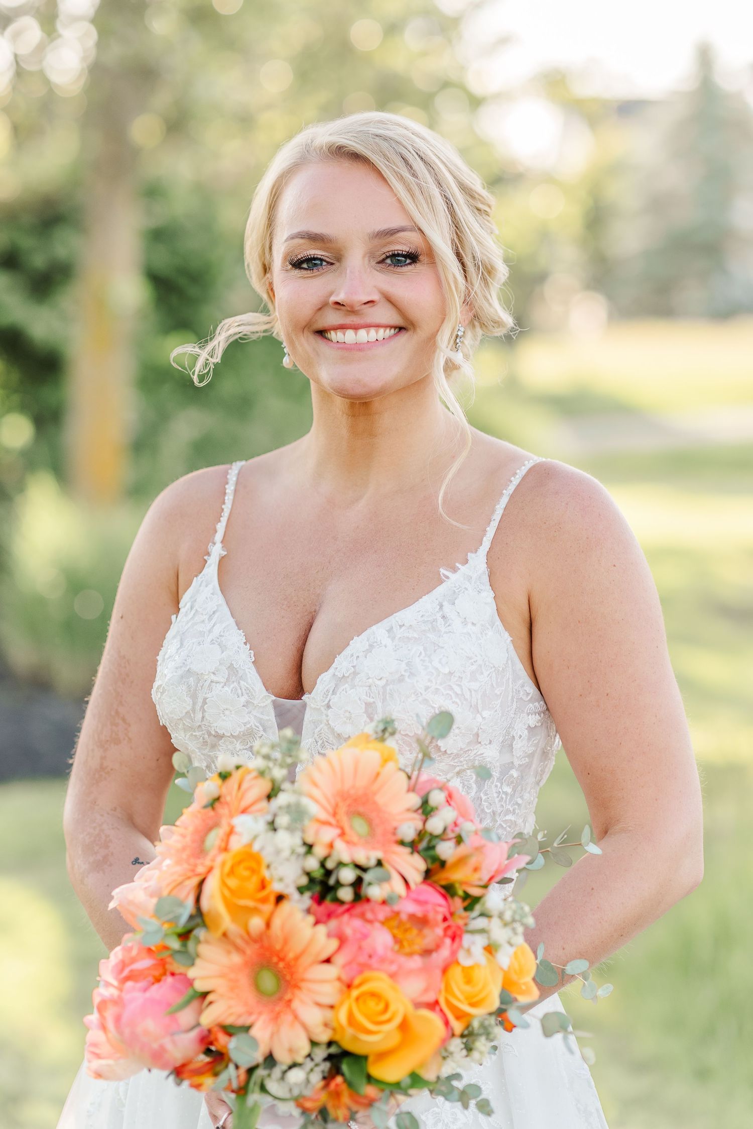 A beautiful bridal portrait featuring a vibrant coral and orange bouquet in an outdoor garden setting.
