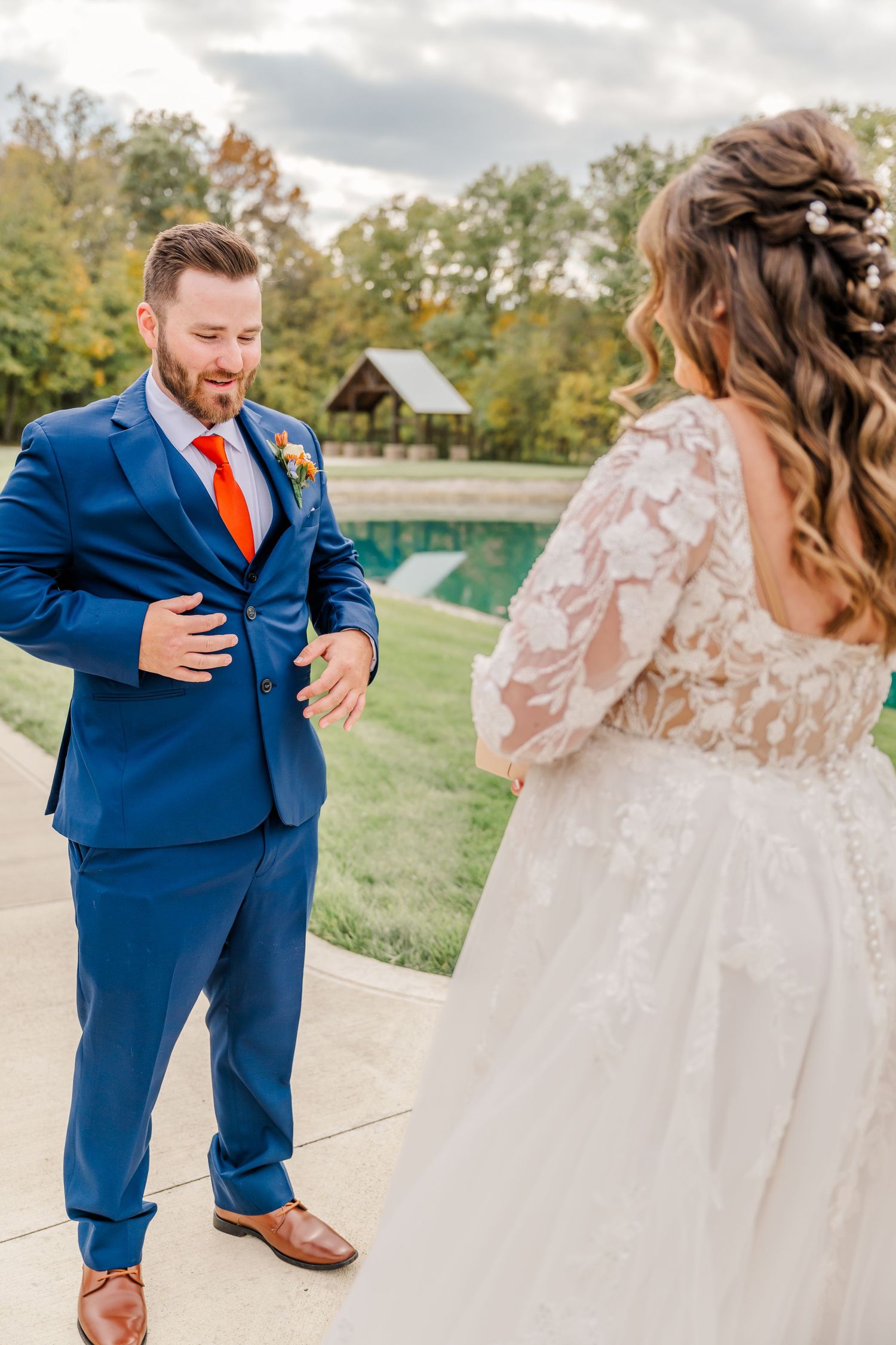 A couple in wedding attire sharing a romantic moment in an outdoor setting with autumn trees.