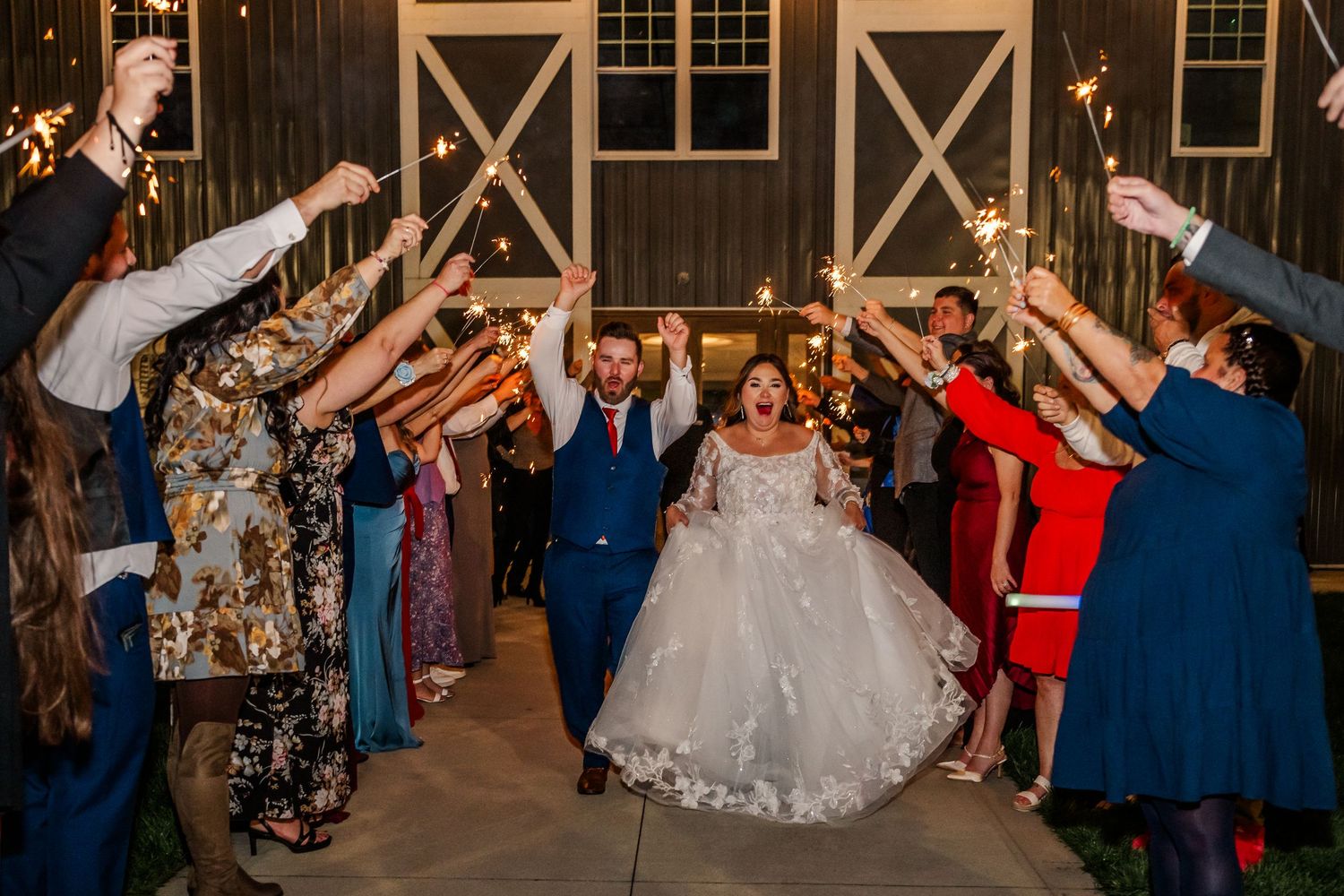 Wedding guests dance together on a rustic barn dance floor during an evening reception celebration.Four Seasons Barn Wedding & Event Venue