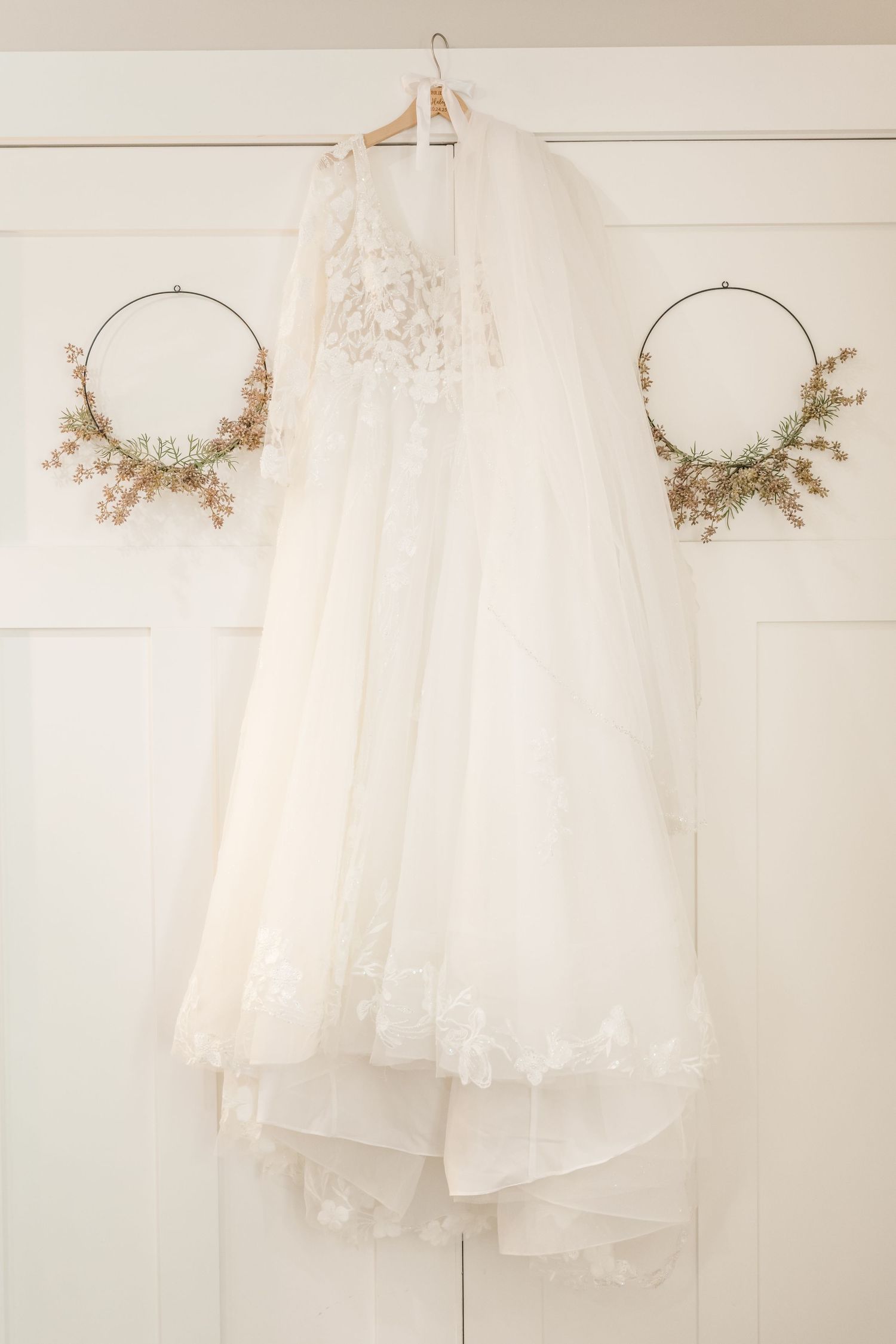 White wedding dresses and veils hanging on display against a neutral wall.Four Seasons Barn Wedding & Event Venue