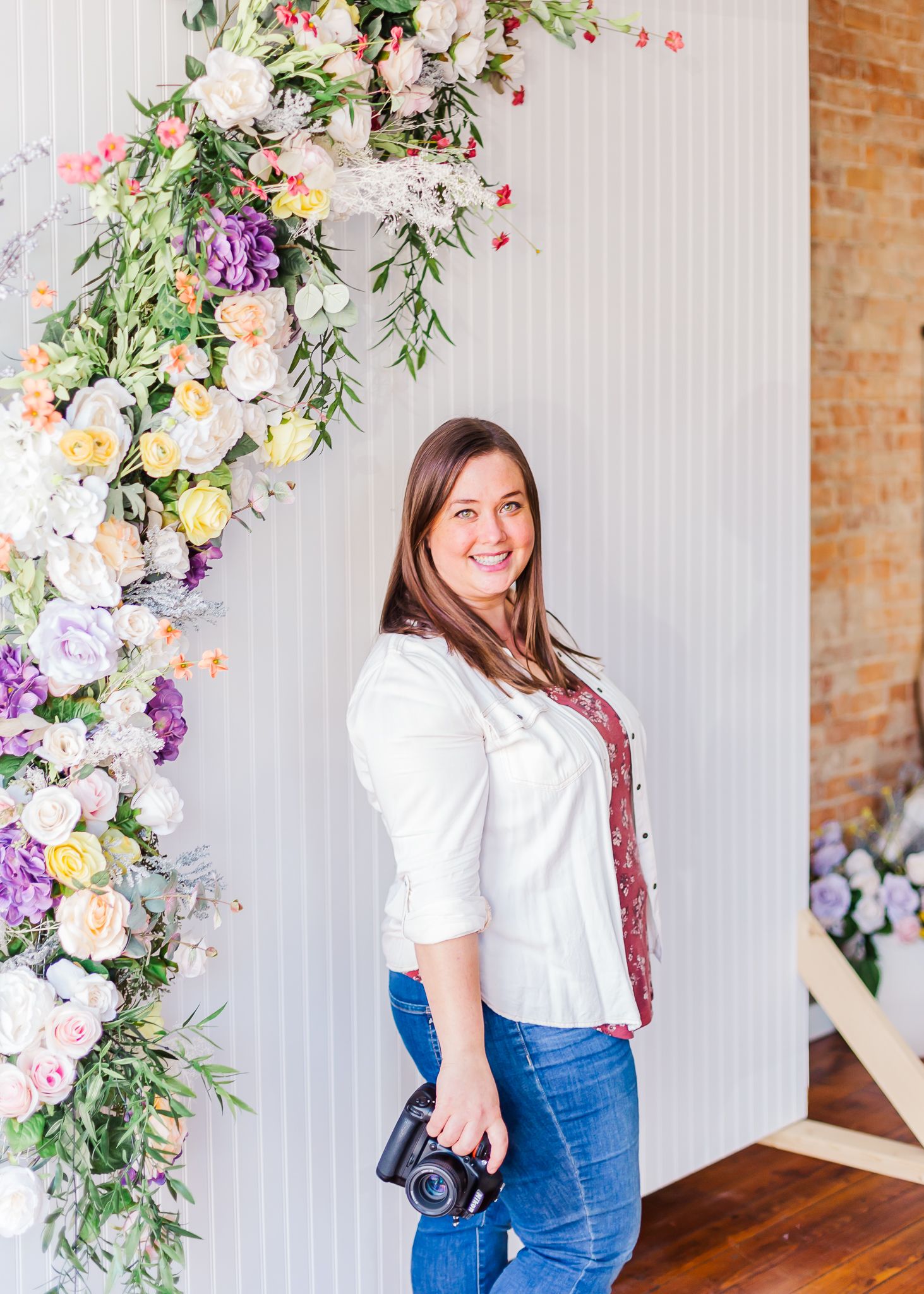 Interior photography studio with floral wall installation and brick accent wall.