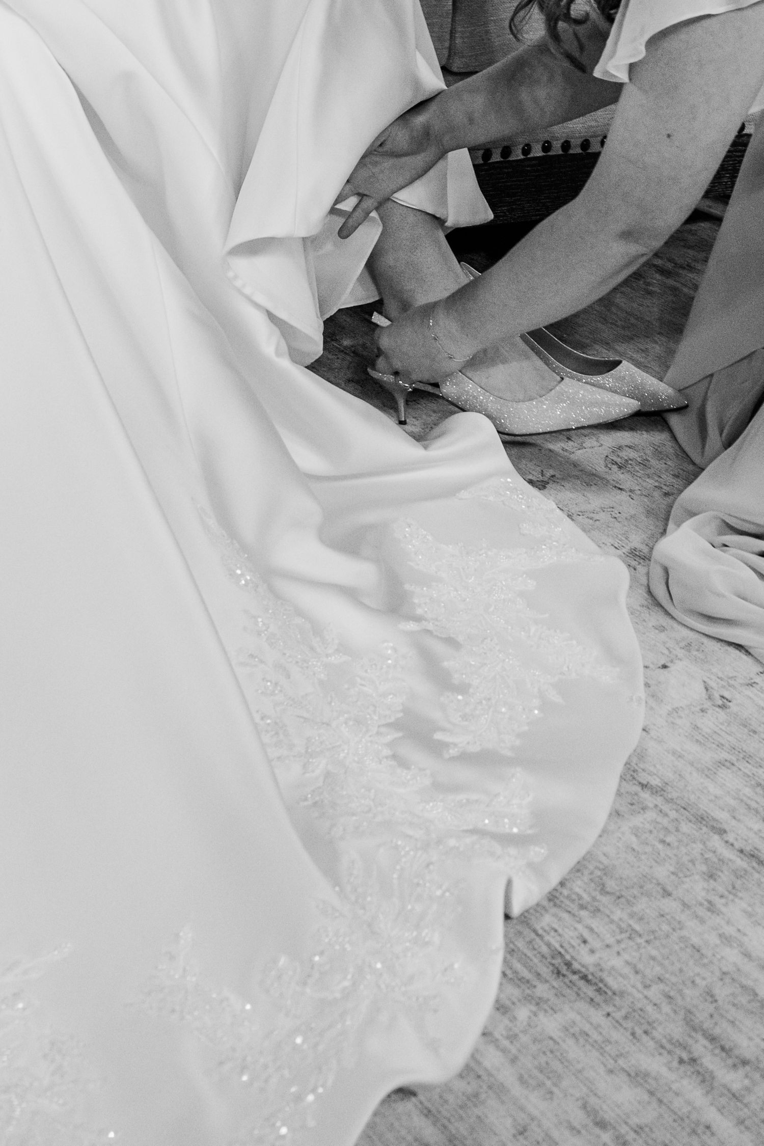 Close-up details of a white wedding dress train with delicate lace patterns on a wooden floor.The Old Barns at Dry Run Farms in Williamsport