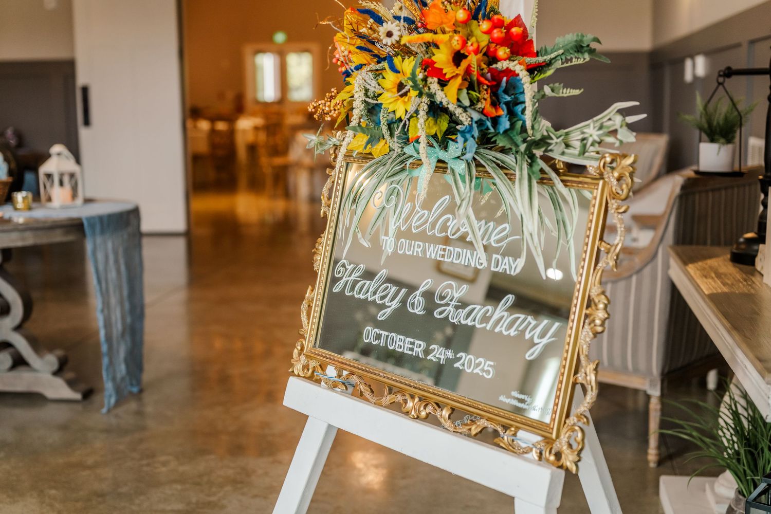 A decorative mirror with gold frame displays elegant welcome text at what appears to be a wedding or special event entrance.