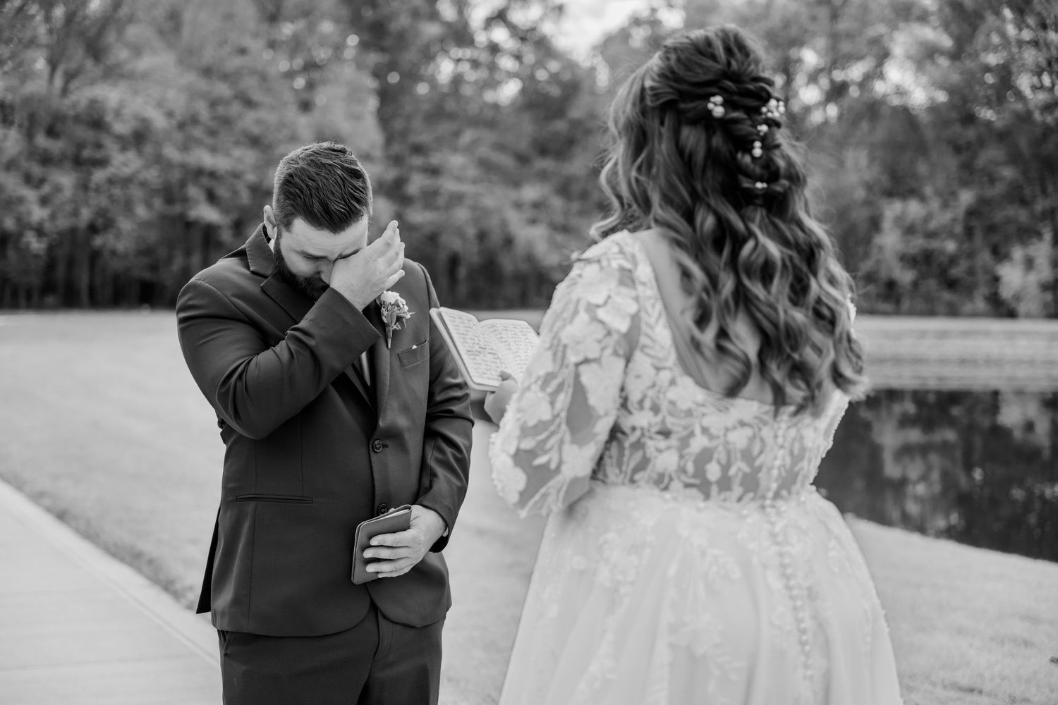 Black and white wedding photo showing an emotional moment between newlyweds during their first look outdoors.