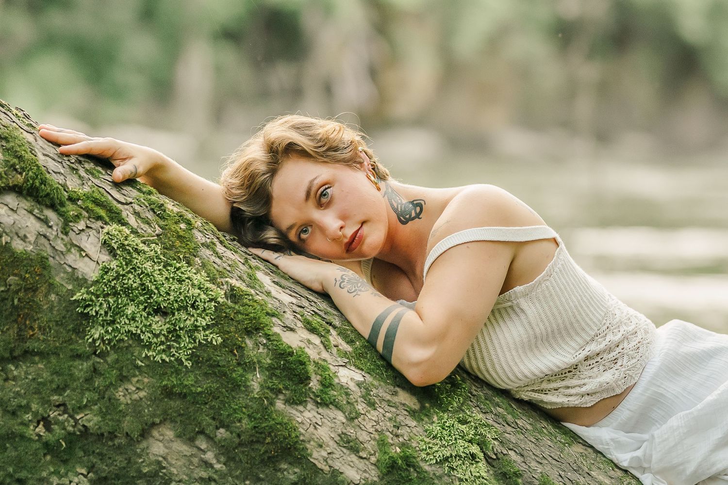 Artistic portraits featuring a white dress against mossy rocks in golden sunlight.