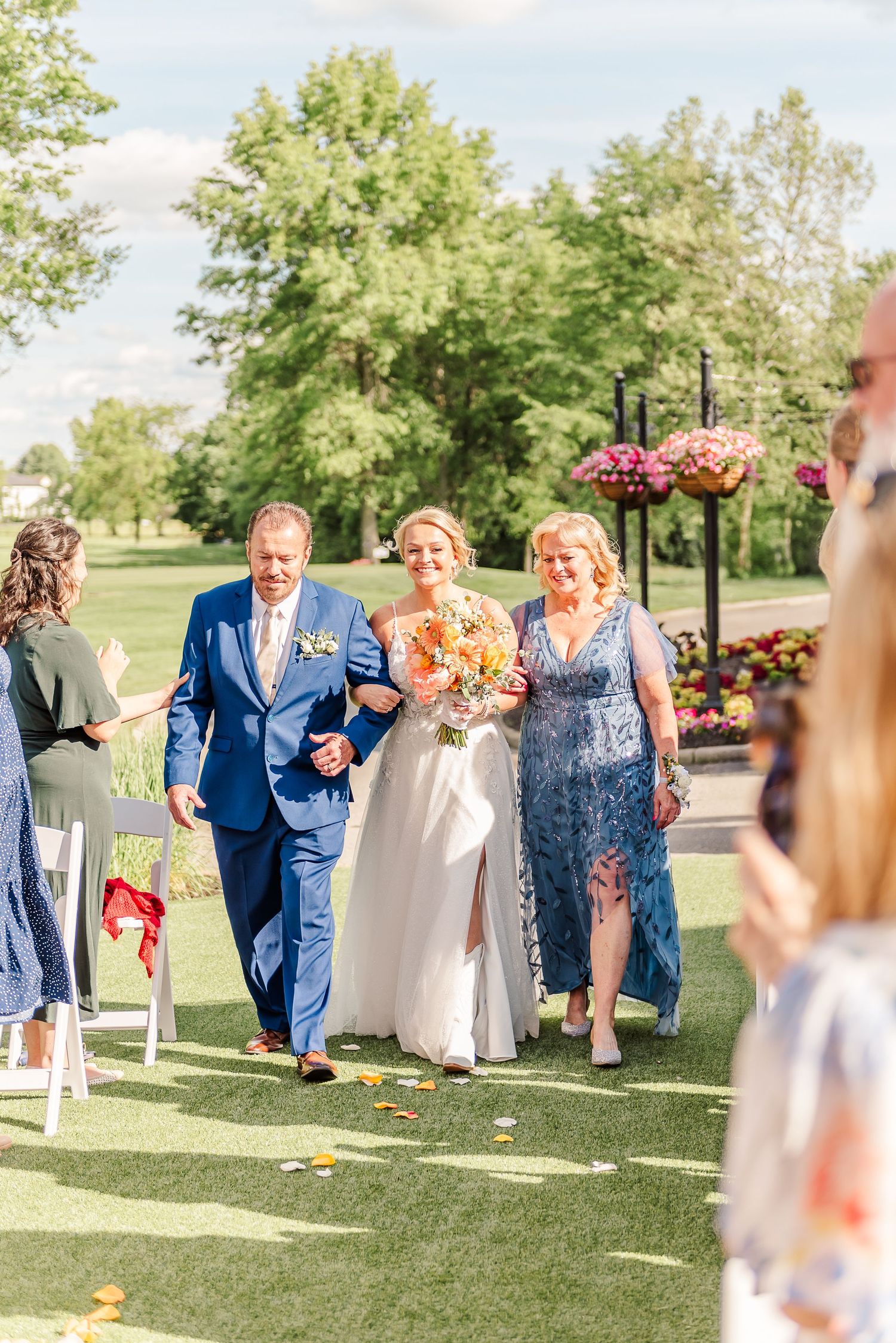Wedding party walking down an outdoor aisle during ceremony processional.