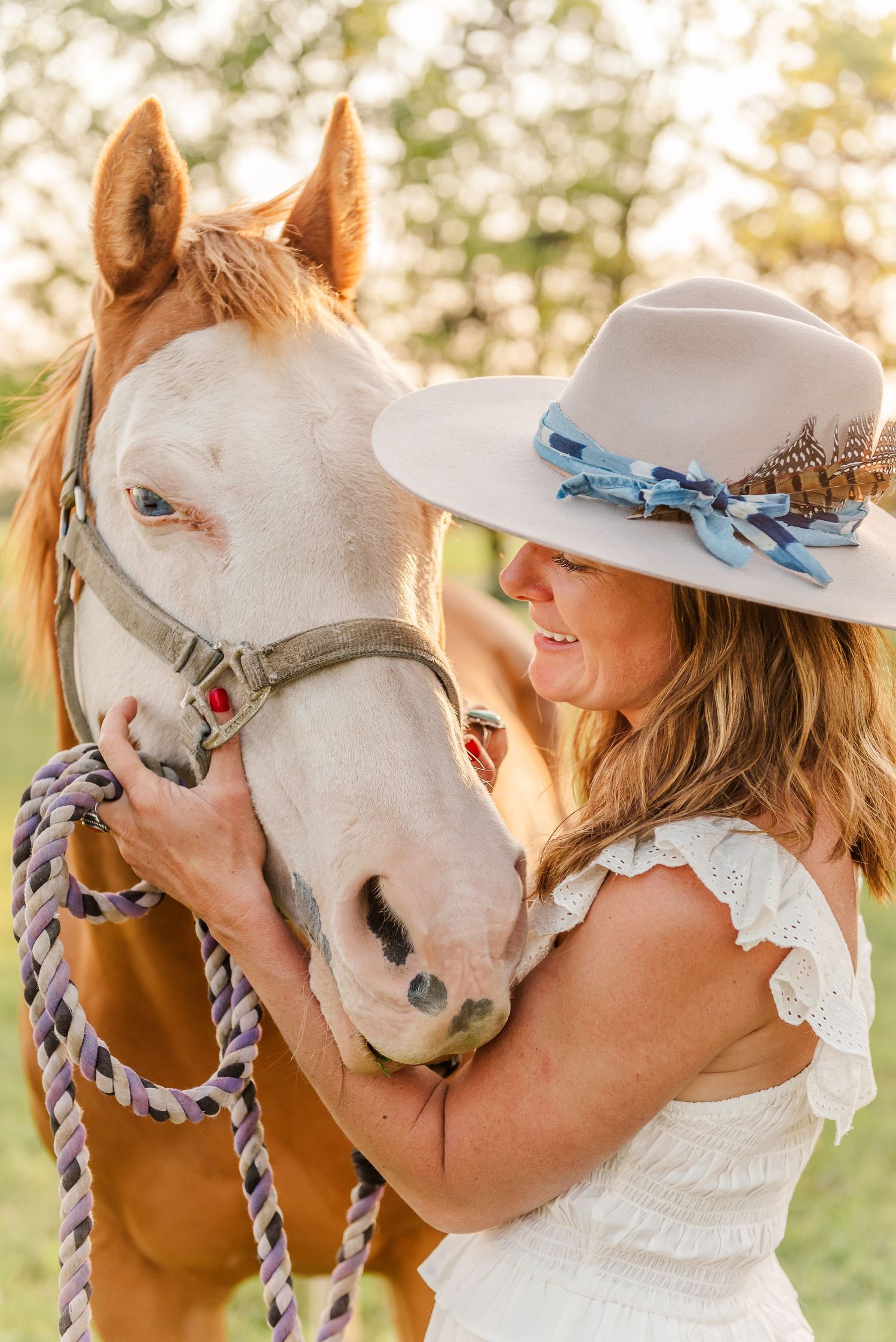 A series of tender moments between a woman in a white dress and hat sharing affectionate moments with a white horse outdoors.