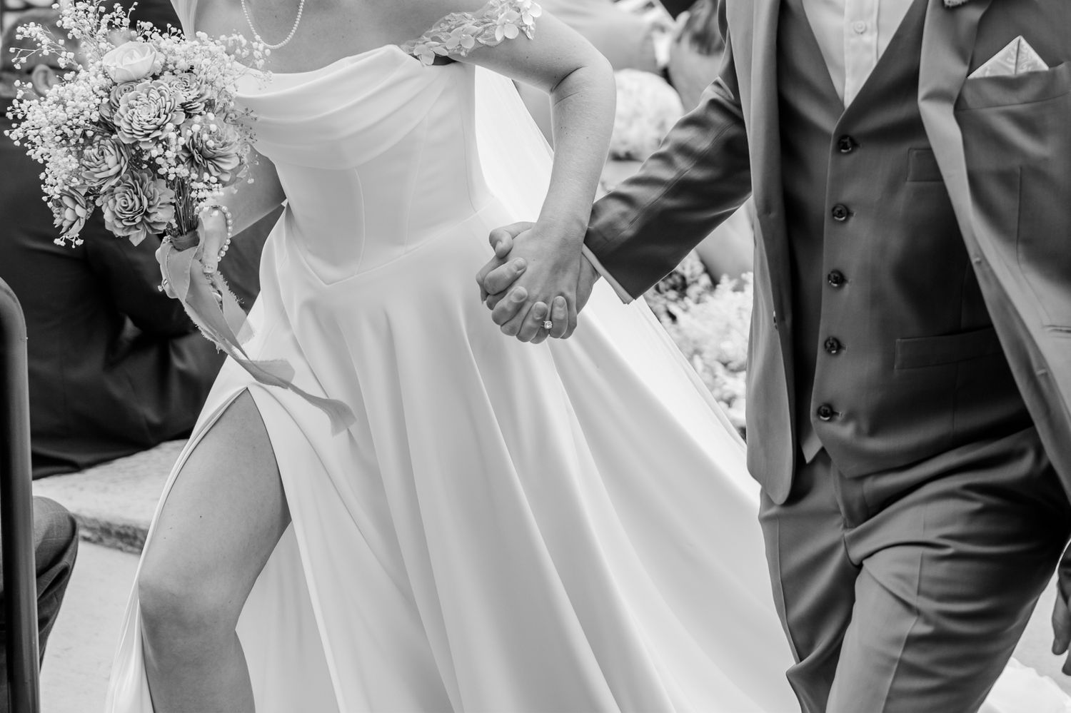 Black and white photo of bride and groom holding hands, bride in elegant gown with slit, groom in suit.The Old Barns at Dry Run Farms in OH.