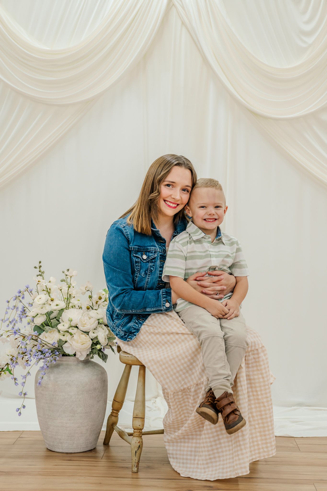 A casual portrait session against white drapes featuring coordinated outfits in blue denim and gingham.