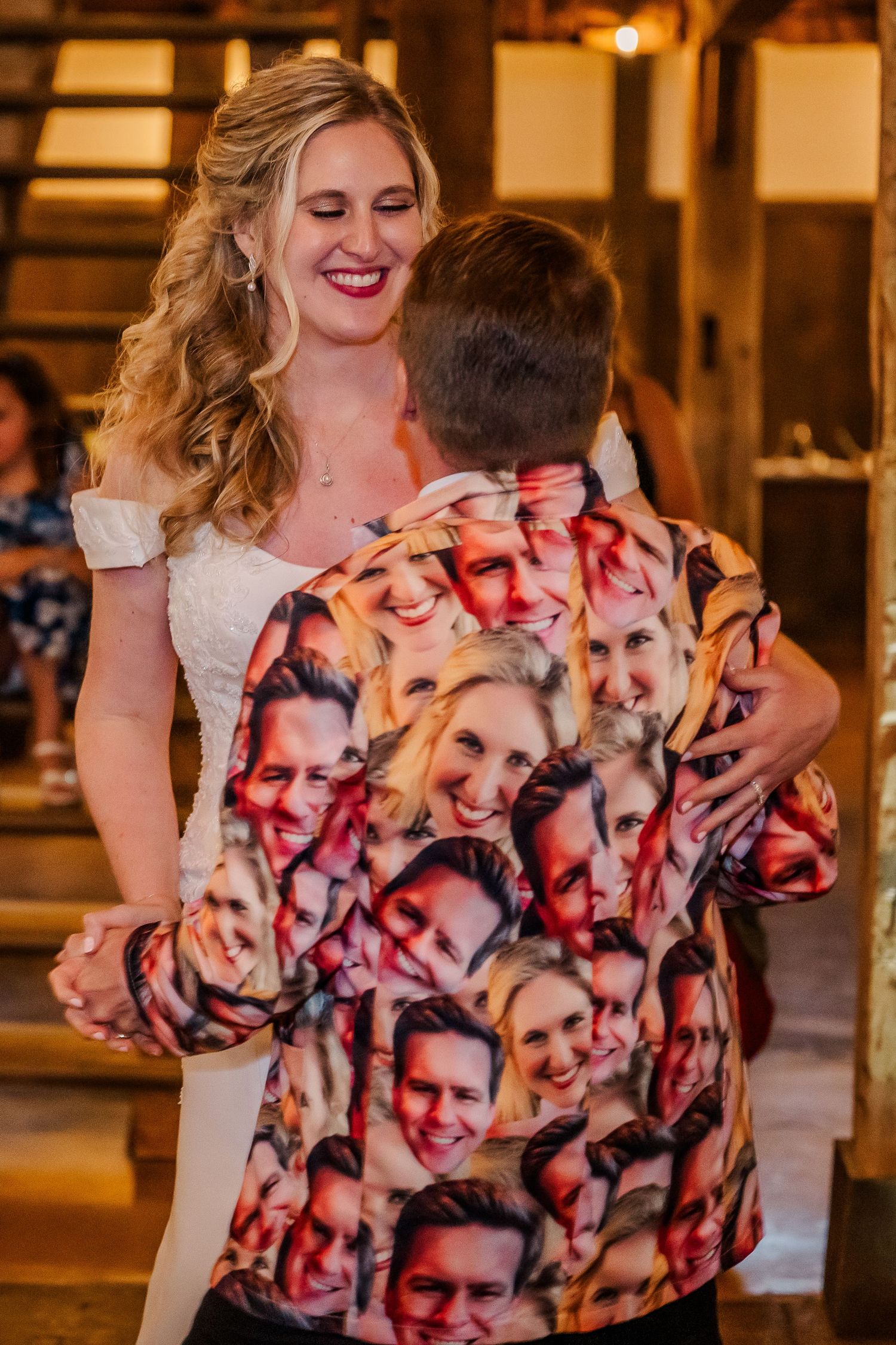 A bride in a white dress laughs while dancing with someone wearing a custom photo-printed suit jacket at a wedding reception.