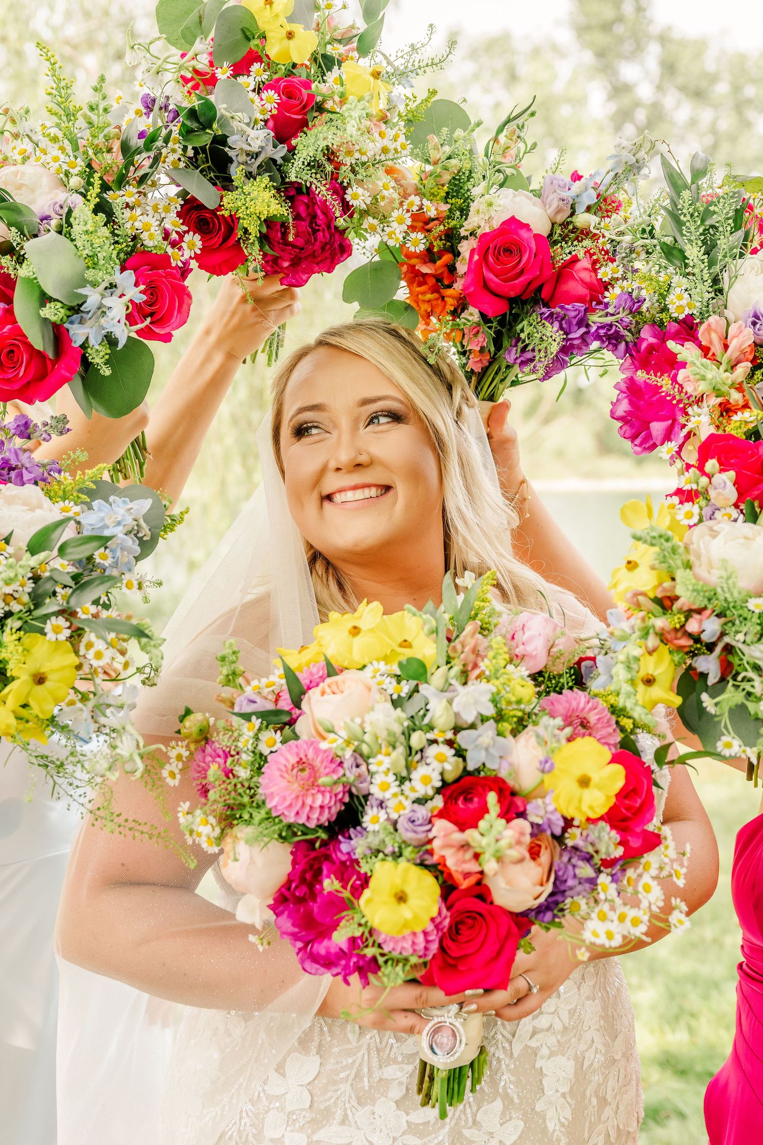 Vibrant summer wedding bouquet with pink roses, yellow daisies, and mixed wildflowers creates a romantic garden aesthetic.