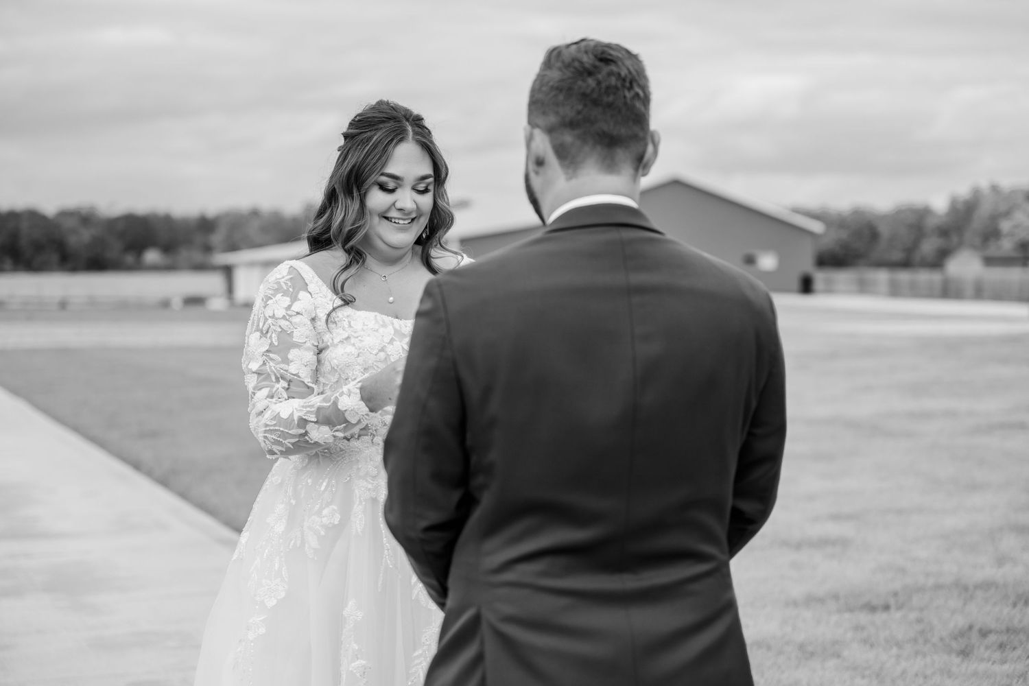 Couple shares intimate first look moment in an outdoor field setting. Four Seasons Barn Wedding & Event Venue