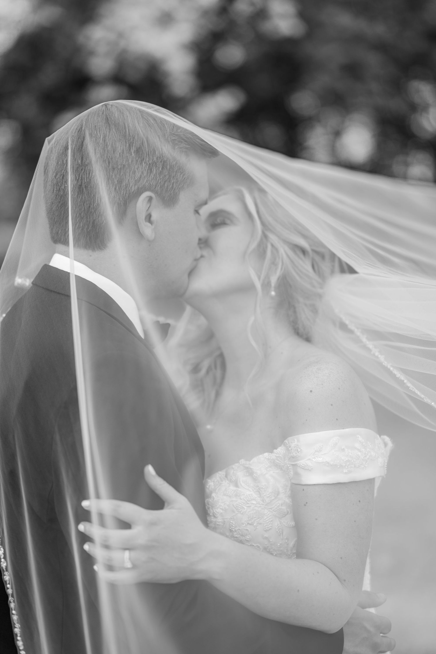 A romantic black and white wedding photo showing a tender kiss under a flowing white veil.The Old Barns at Dry Run Farms in Williamsport, OH