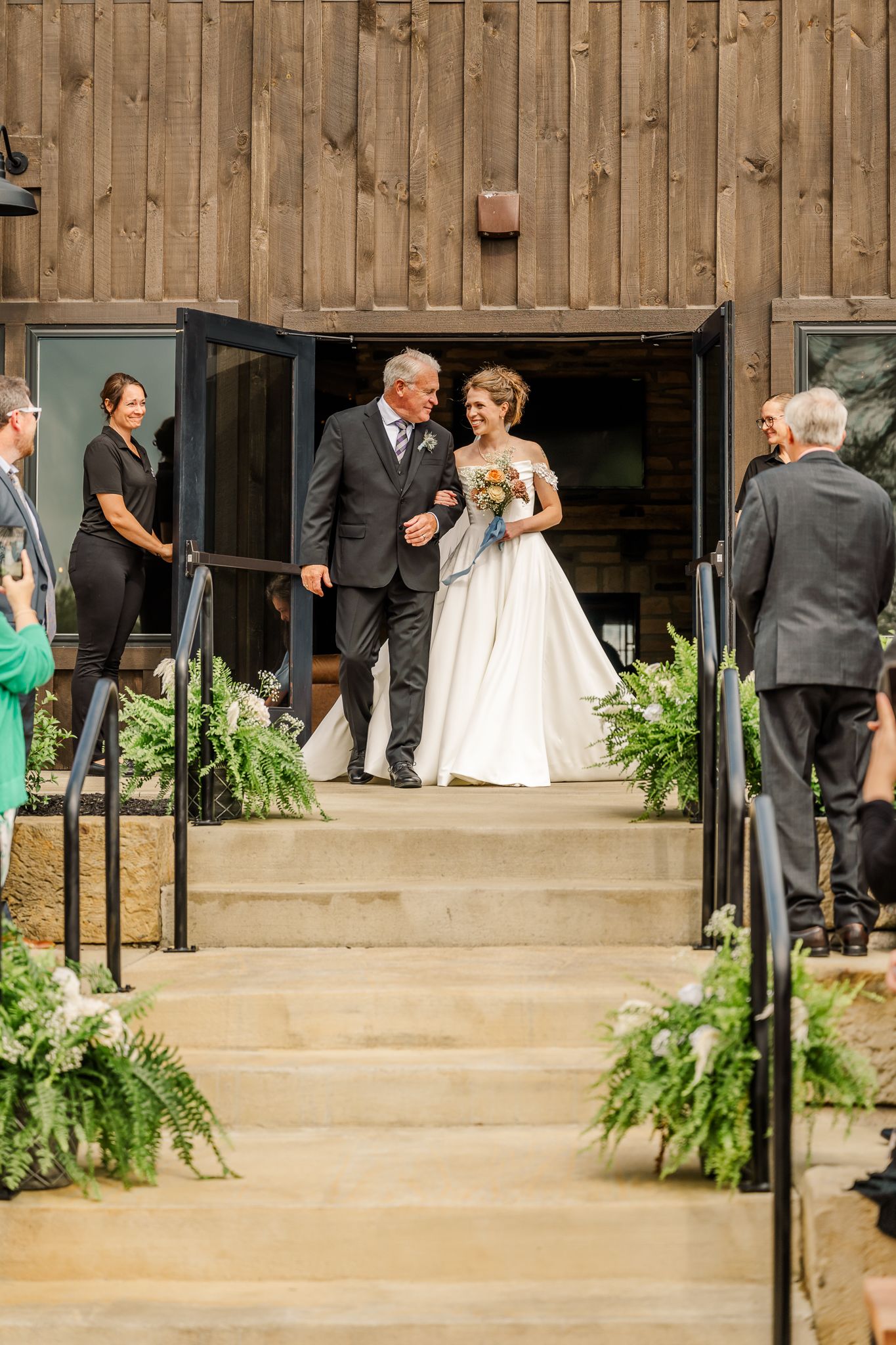 Bride walks down outdoor wedding steps with escort at rustic barn venueThe Old Barns at Dry Run Farms in Williamsport, Ohio.